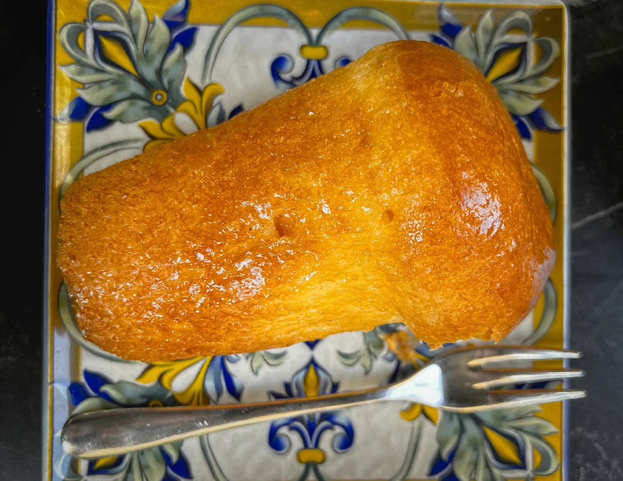 Babà. Overhead shot on ornate plate with a fork.