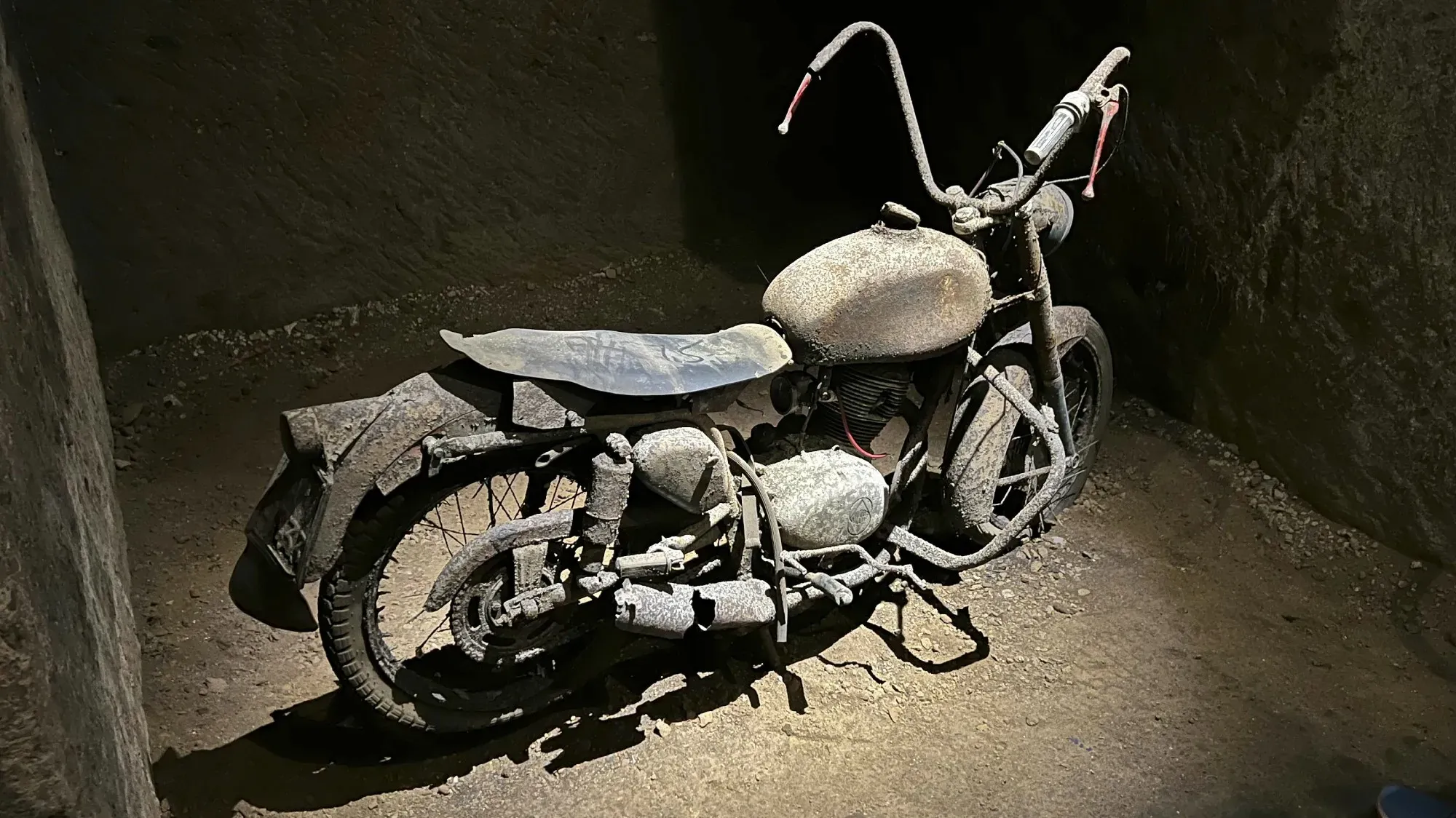 Rusty motorbike lit by an overhead spotlight in the Bourbon Tunnels.