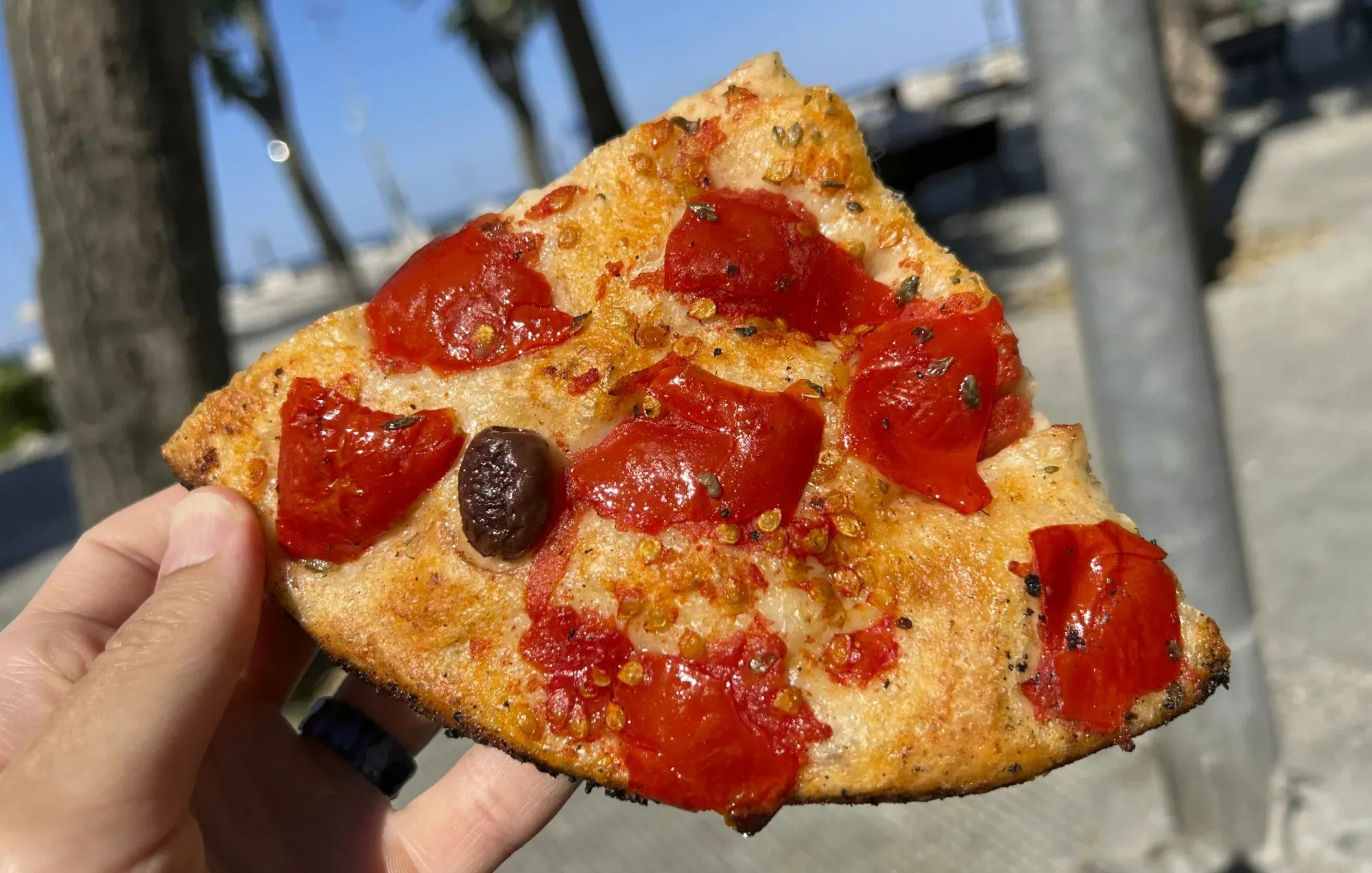 Focaccia. Straight shot held in hand with Bari coastline in the background.