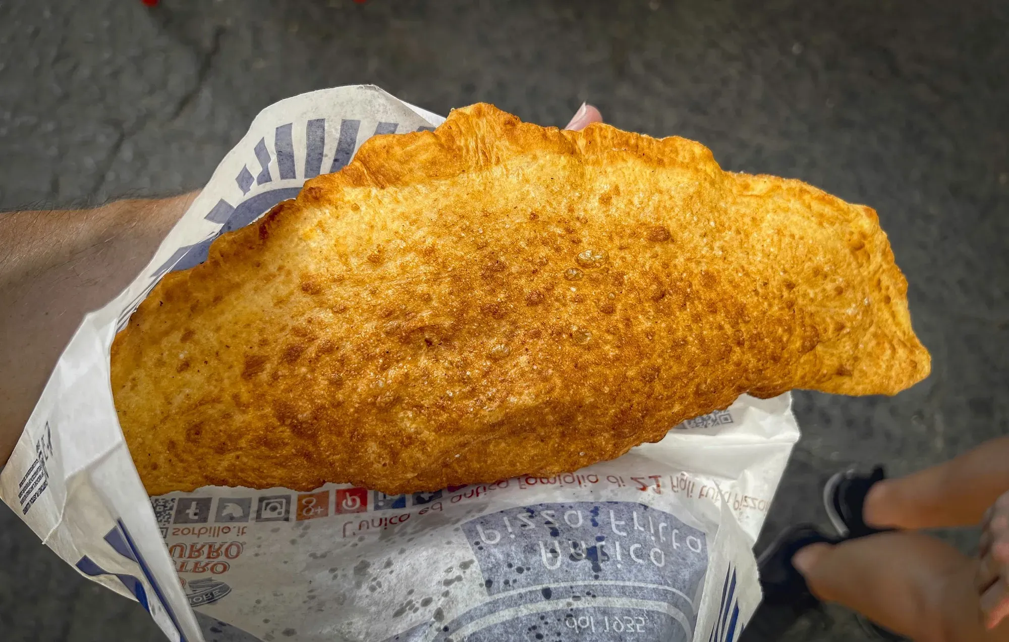 Fried Pizza. Overhead shot holding street food fried pizza in hand.