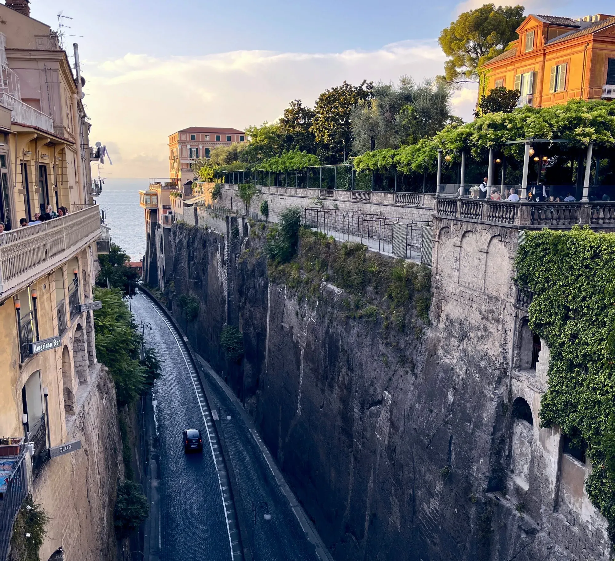 An road in between two tall rock walls leading to the sea.