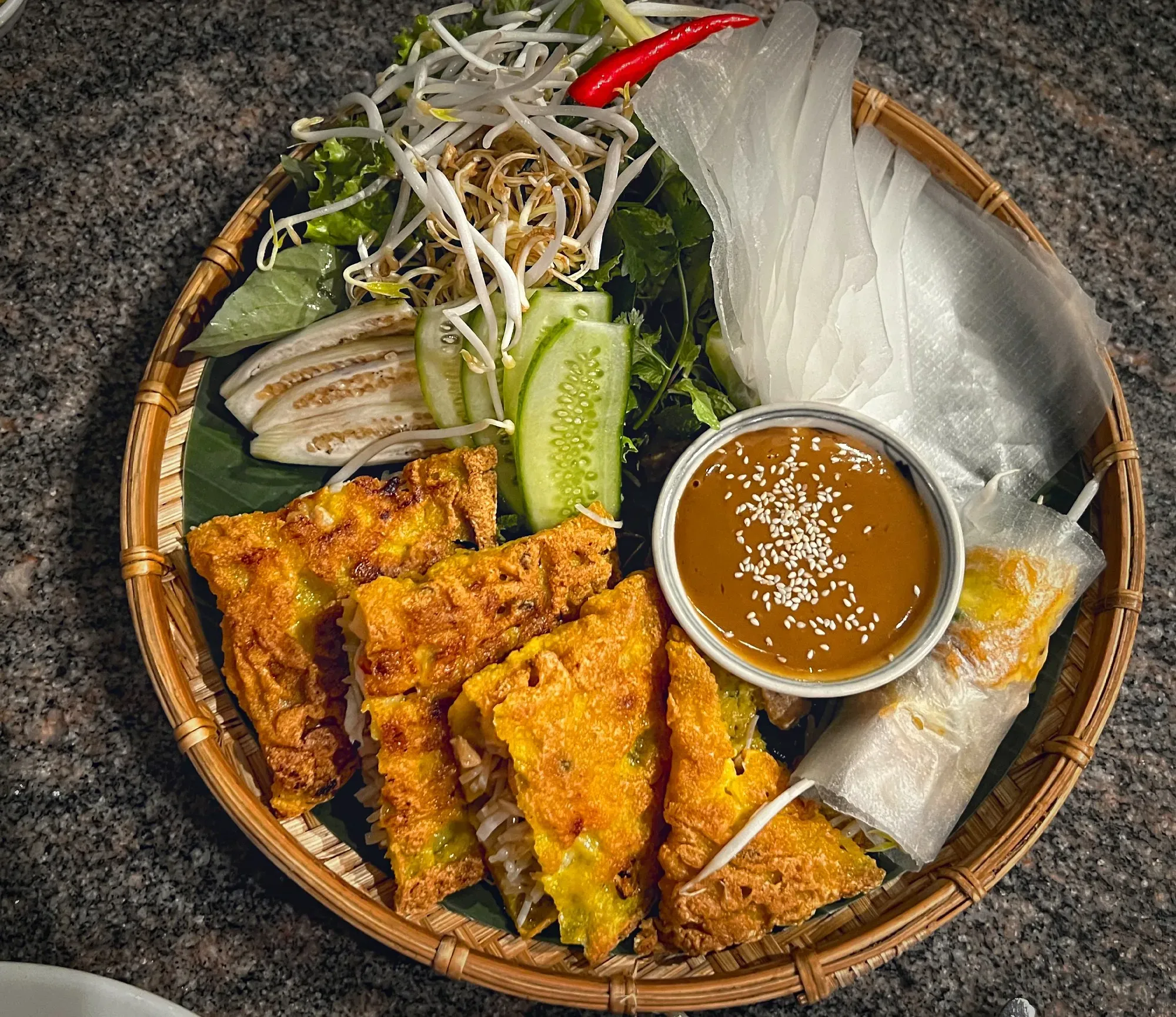 Bánh Xèo precut into 4 quarters with all fixings on a platter, overhead shot.