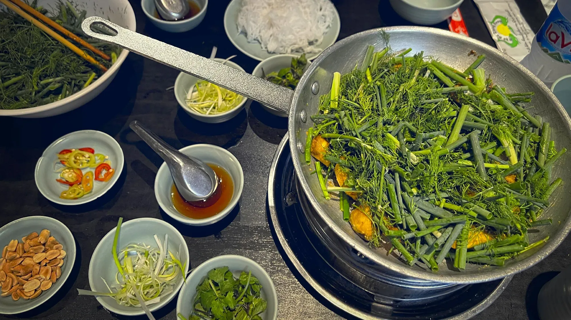 Chả cá on the table. Cooked in a skillet on the table with many garnish dishes. Overhead shot.