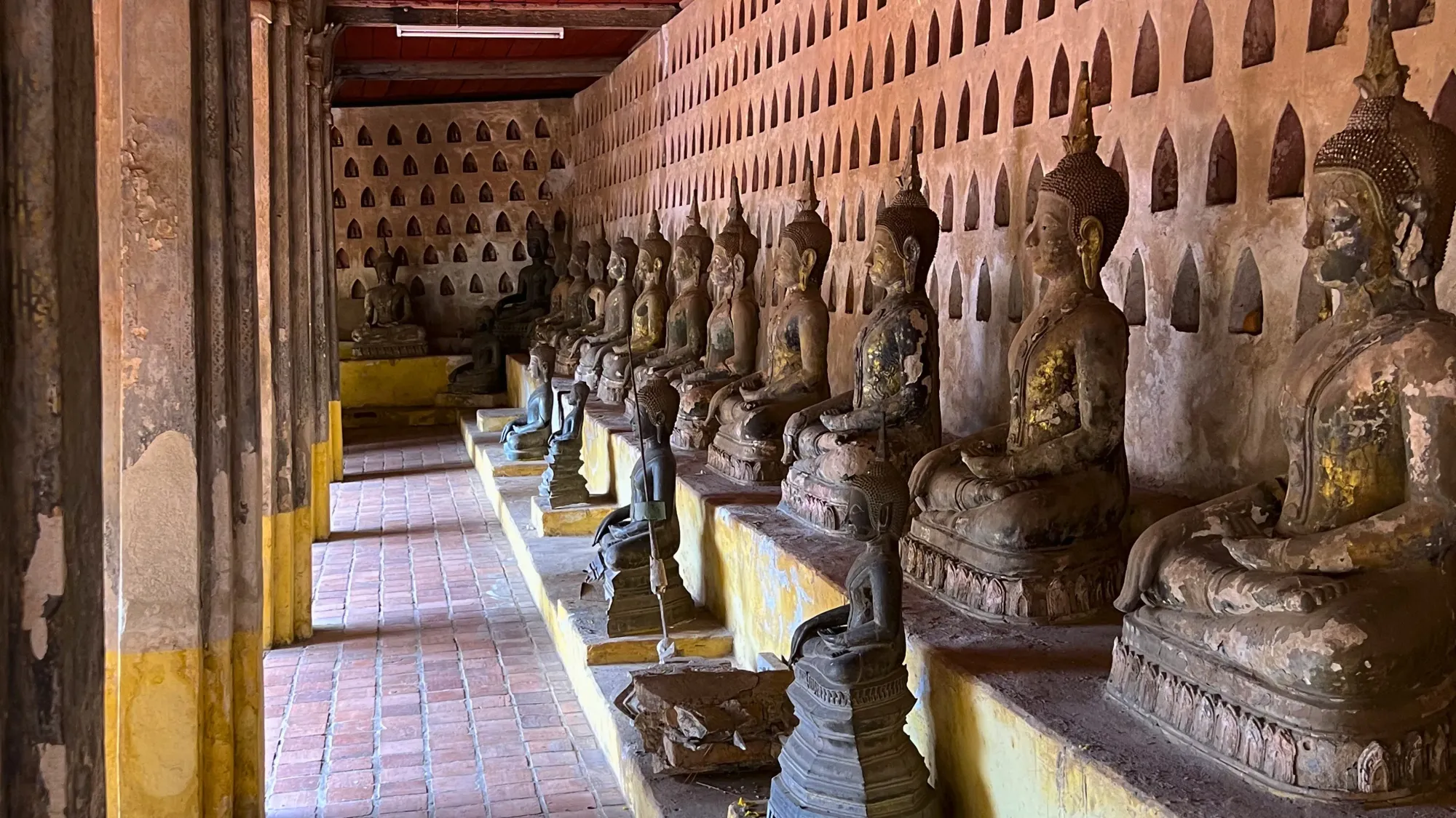 Successive seated buddha statues lined up on a bench in the temple