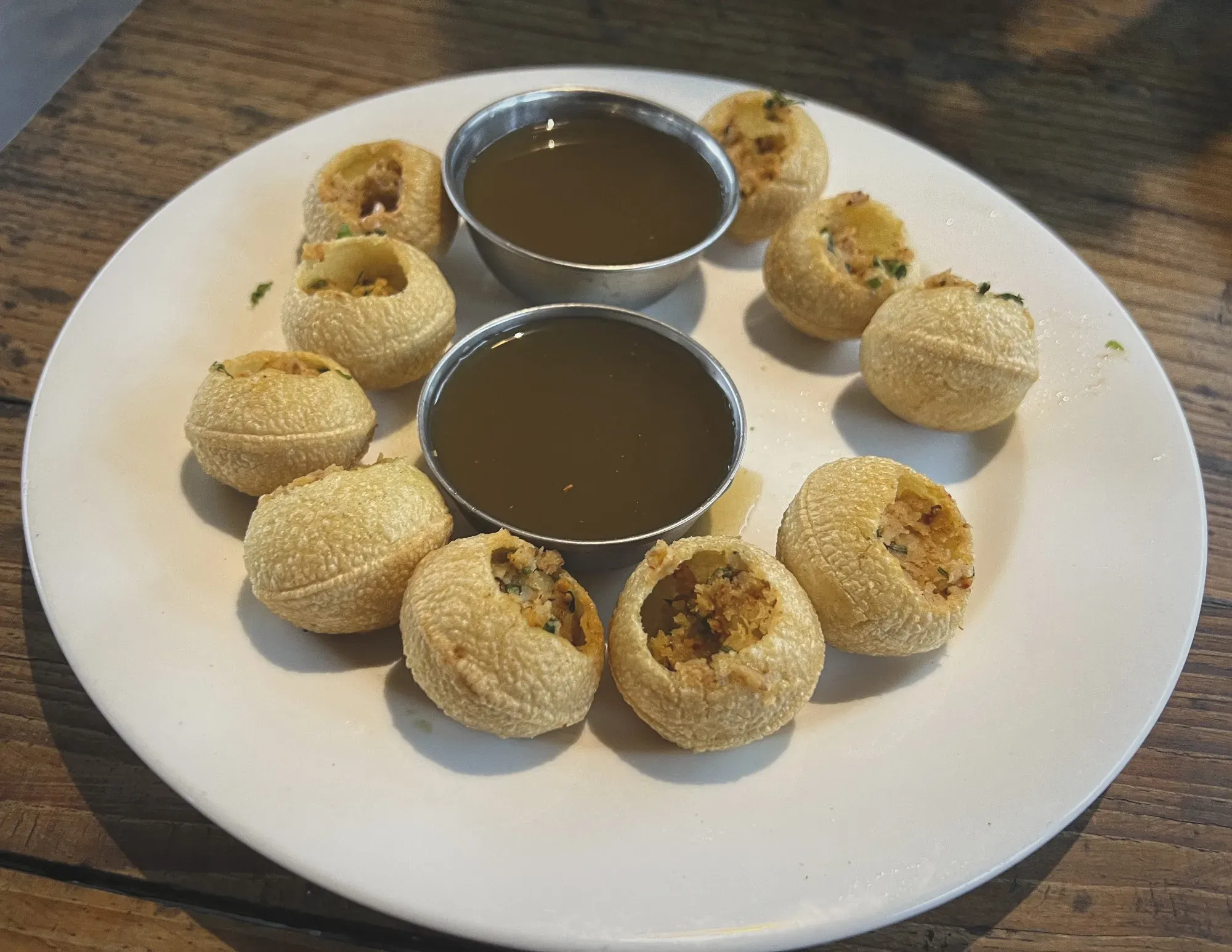 Plate of Pani Puri with two dipping containers, angled shot.