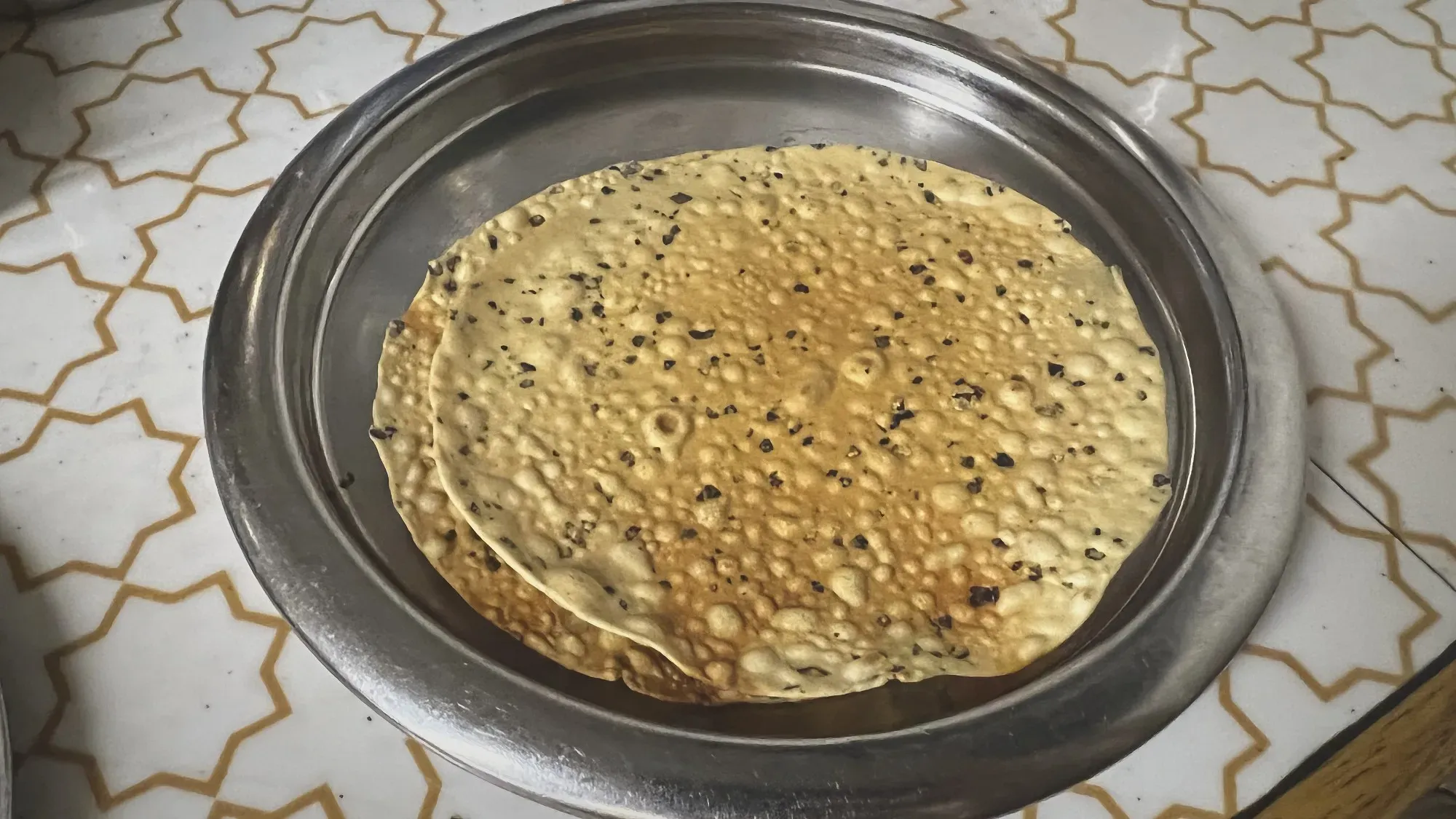 Angled shot of two papad on a silver plate.