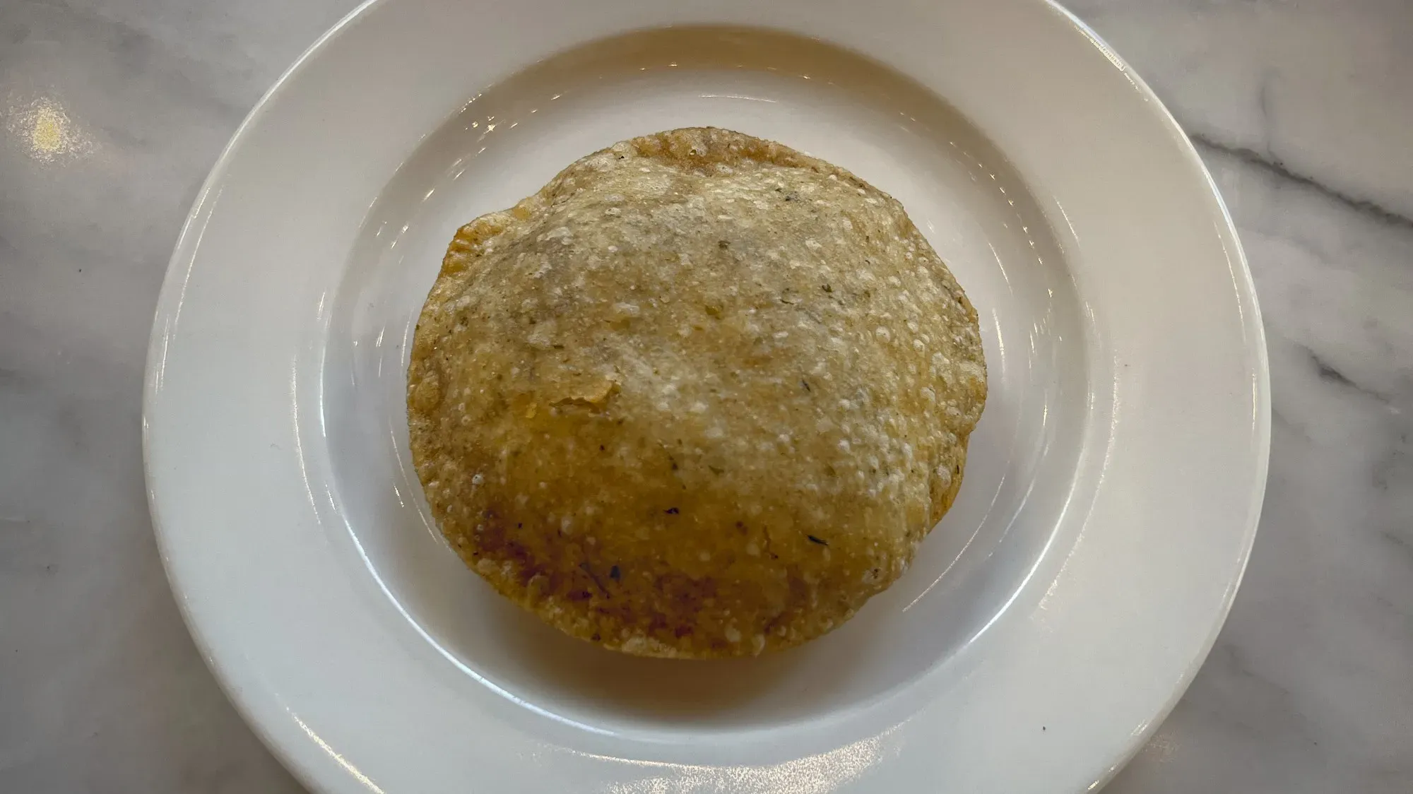 Overhead shot of a single puri on a plate.