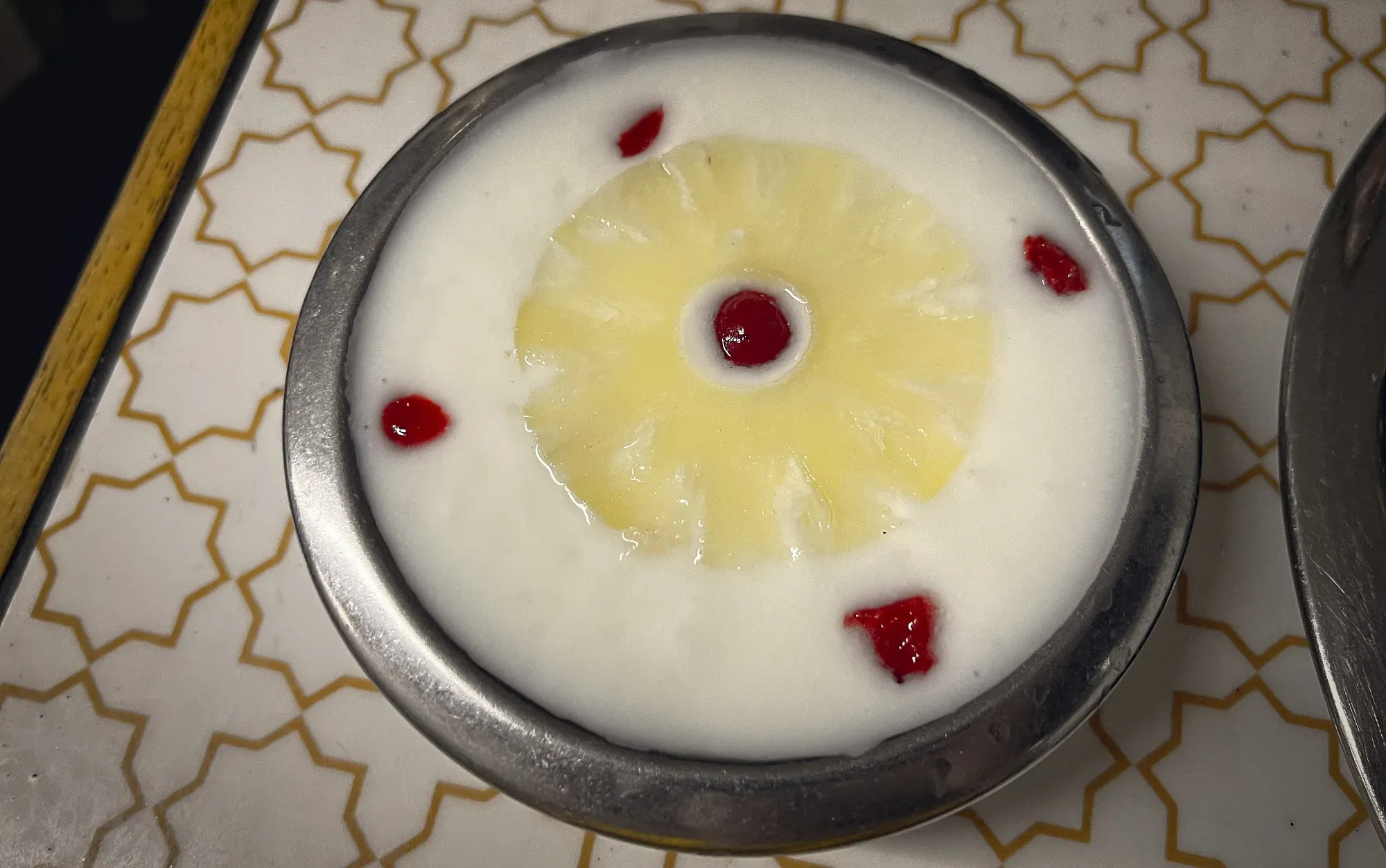 Raita with a sliced pineapple and pomegranate seeds floating on top, overhead shot.