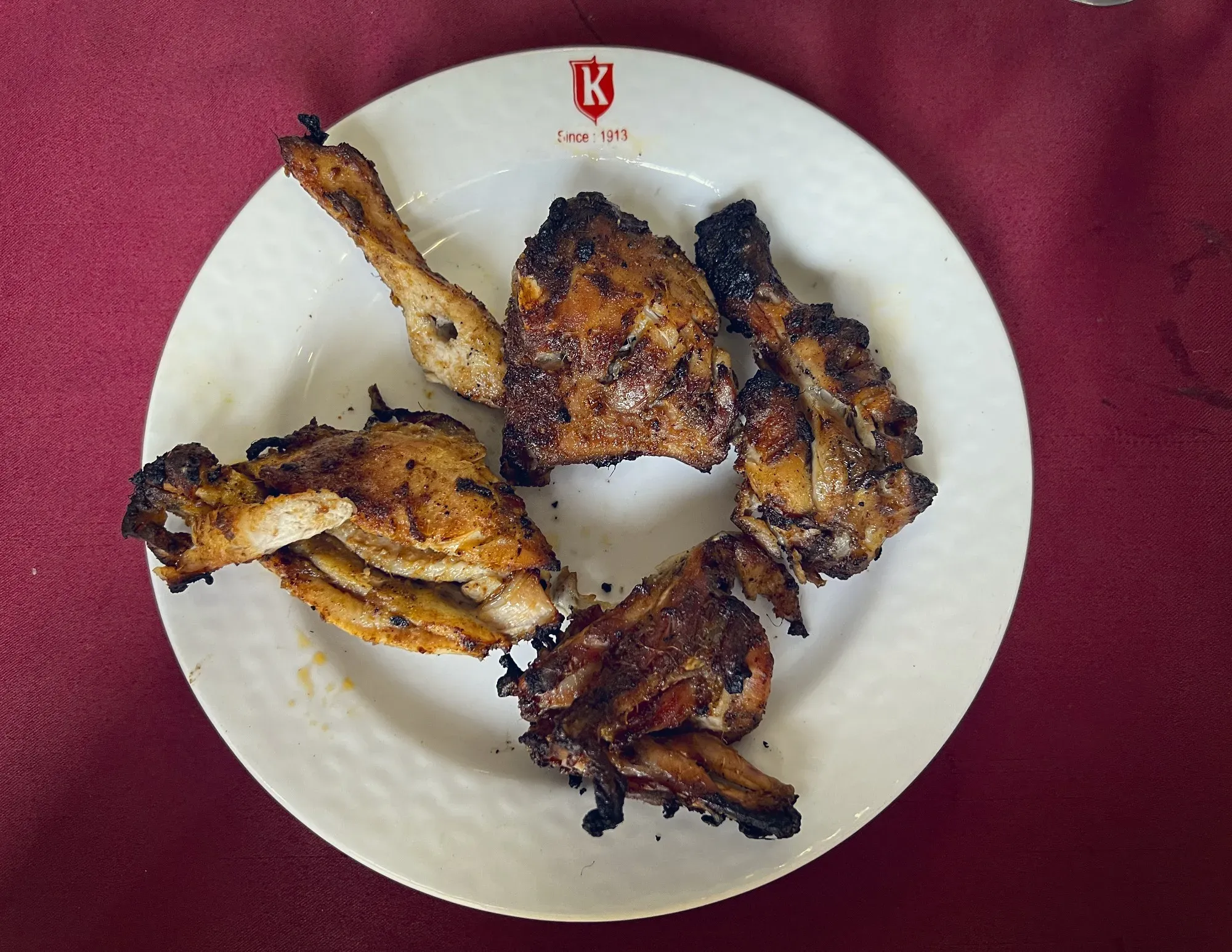 Five pieces of Tandoori chicken on a plate, overhead shot.