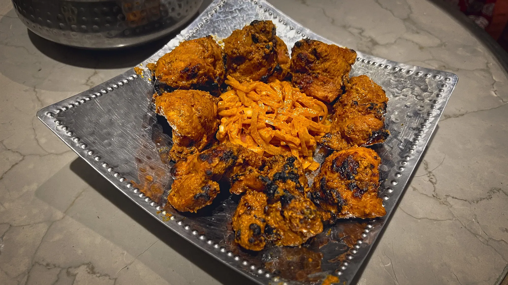 Tikka on a silver serving platter, angled shot.