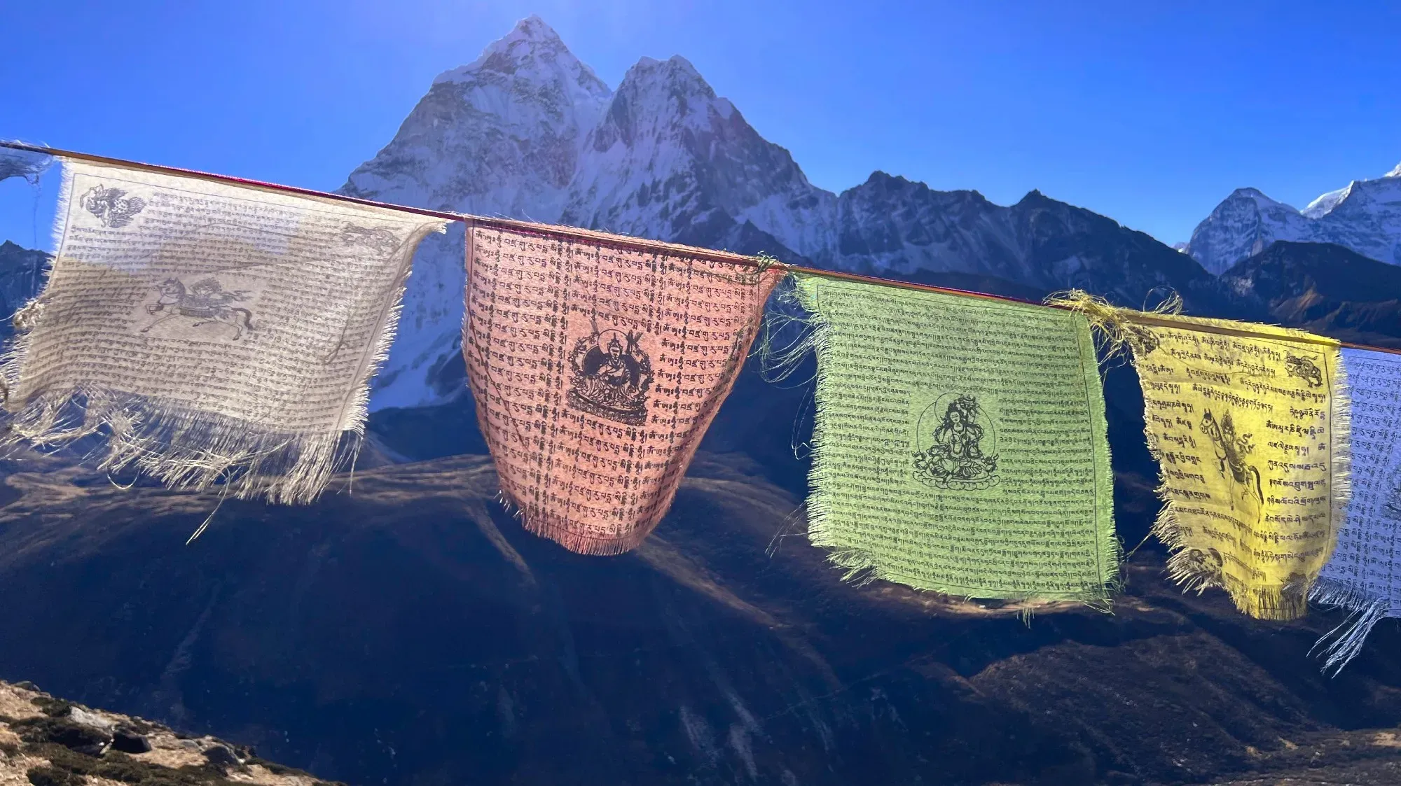 Worn white, red, green, and yellow prayer flags hanging