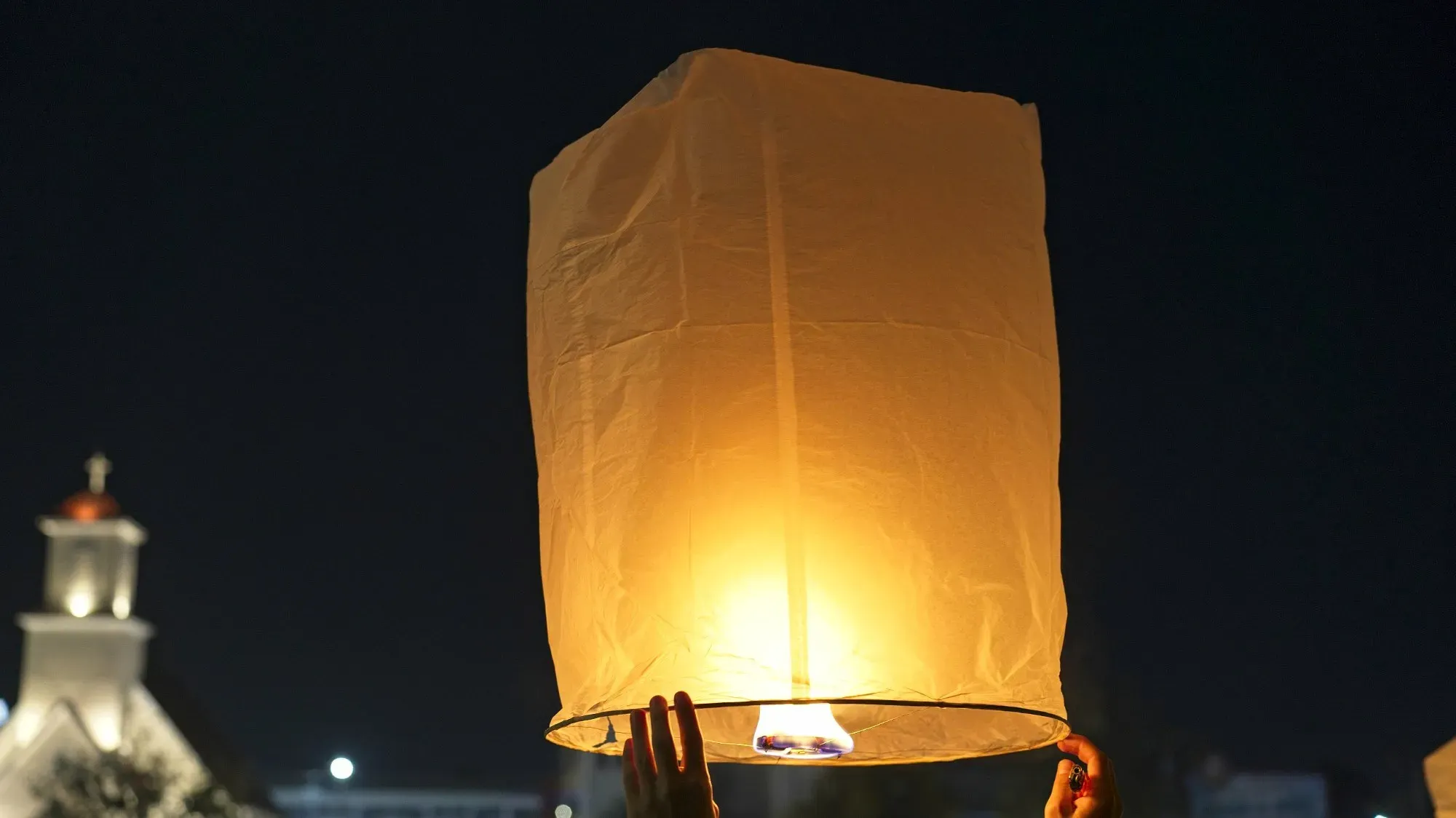 Close up image of hands holding a lit floating lantern