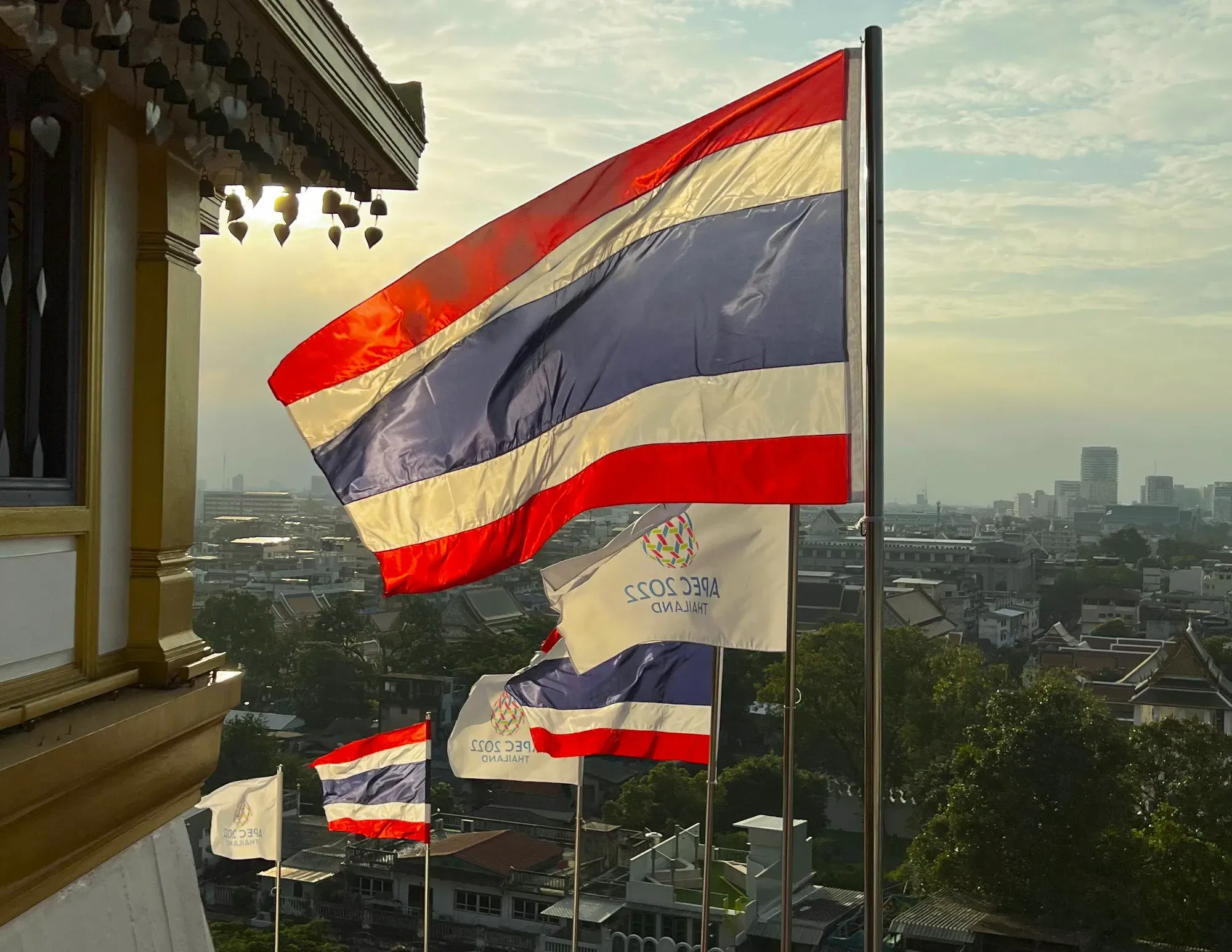 Alternating Thai and APEC 2022 flags flying in reverse with the wind overlooking the city
