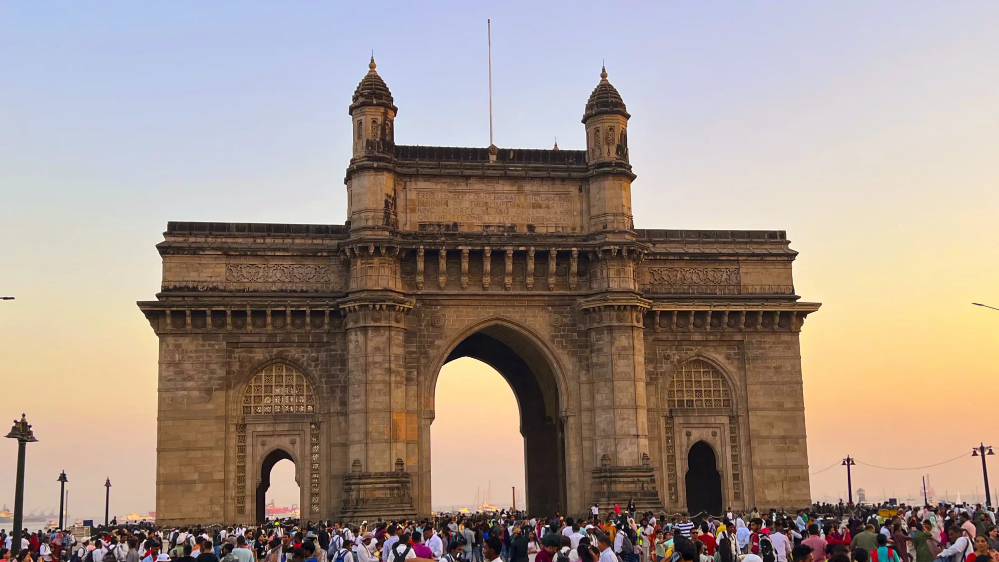 Three arches comprising the Gateway to India with many tourists standing in front of it