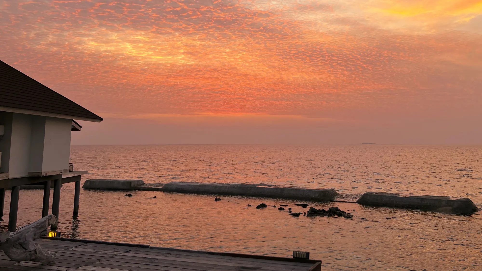 Pink and orange sky reflecting in the water by the bungalows