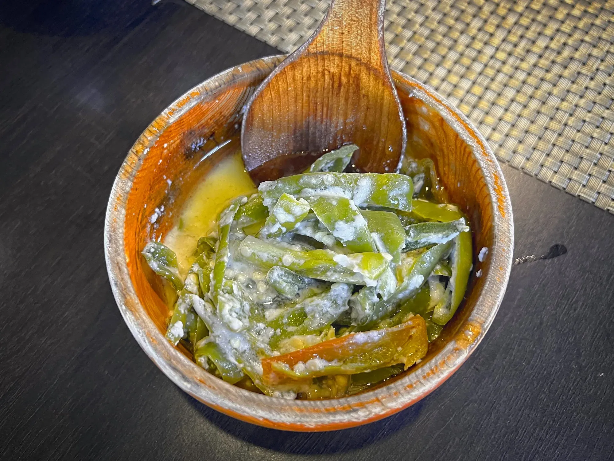 Close up overhead shot of Ema Datshi in wooden bowl with wooden spoon.