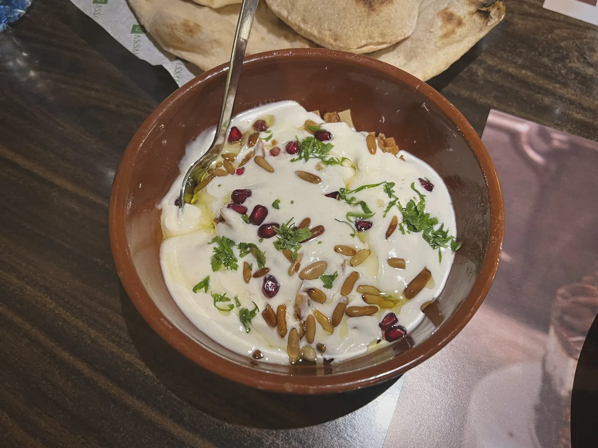 Fatteh in a bowl with bread in the background. 