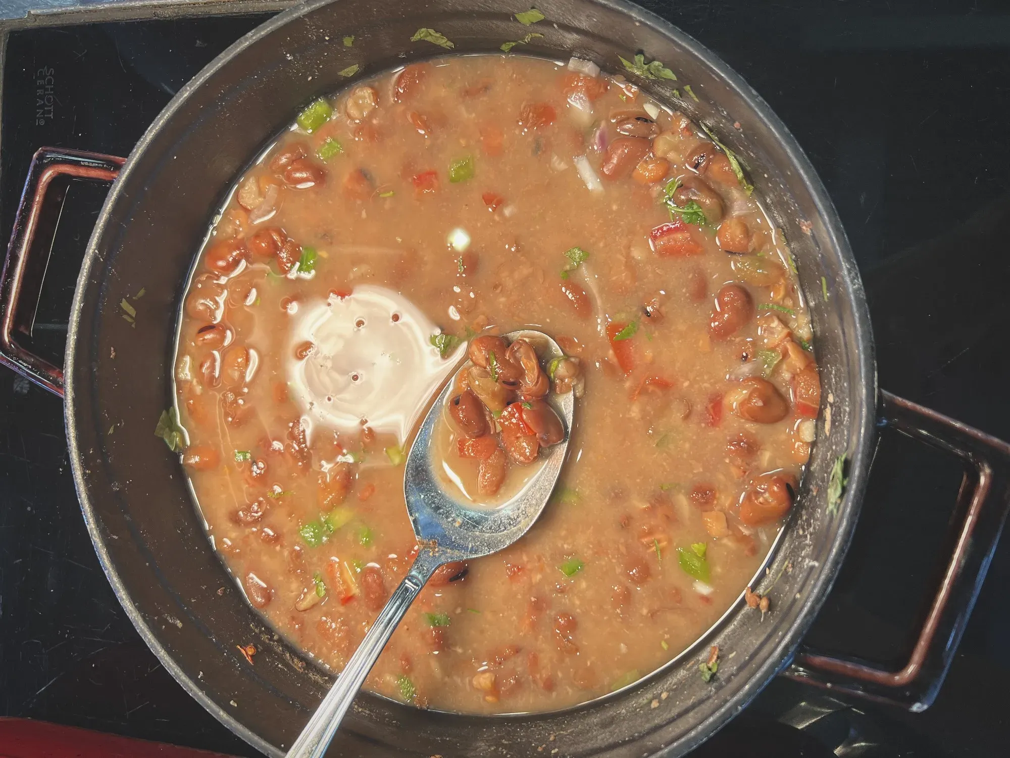 Skillet of Ful Medames with a spoon showing the bean, overhead shot.