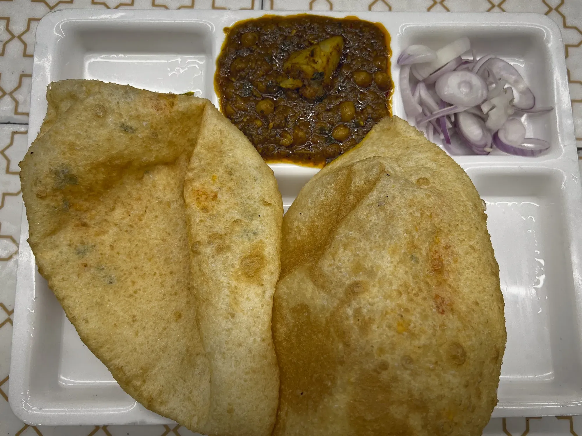 Tray with two large Bhature and a serving of Chole "curry", overhead shot.