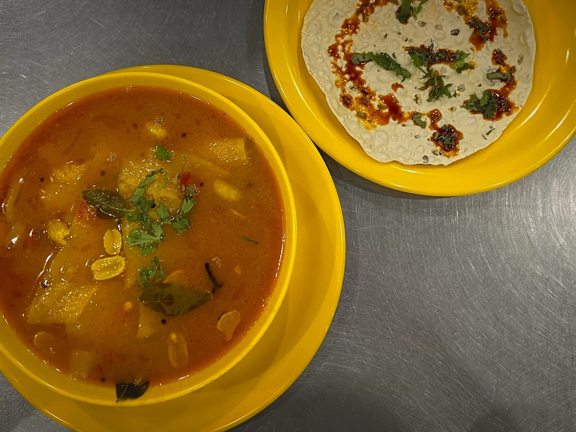 Dal Dhokli in a bowl with a side plate of papad, overhead shot.