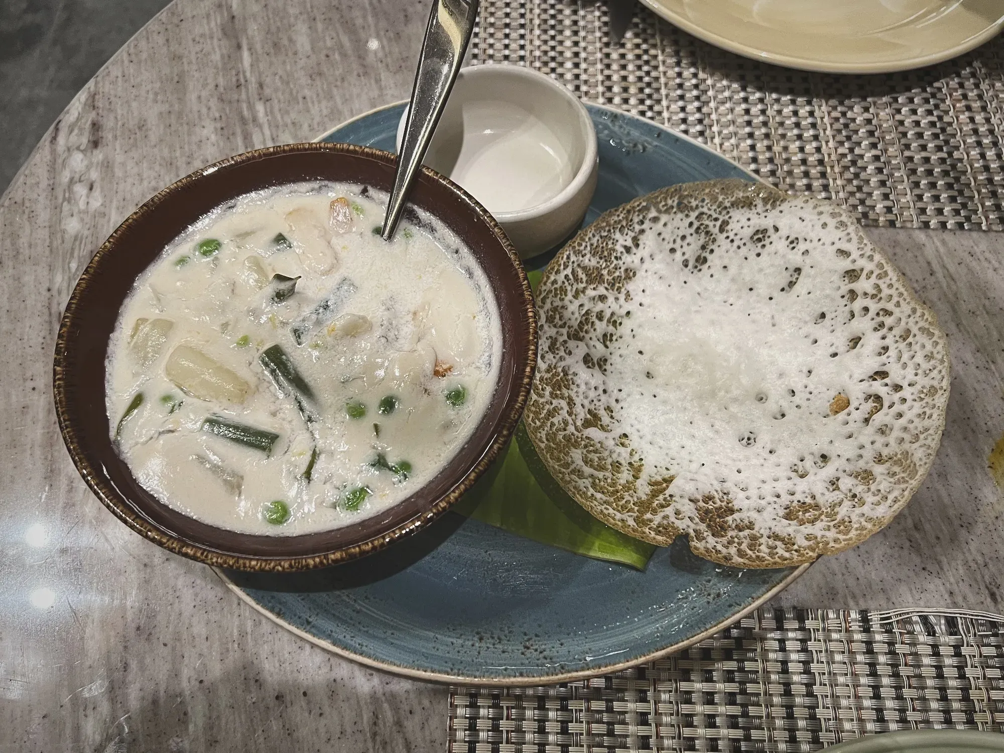 Overhead shot of a bowl of Ishtu next to a side of appam.