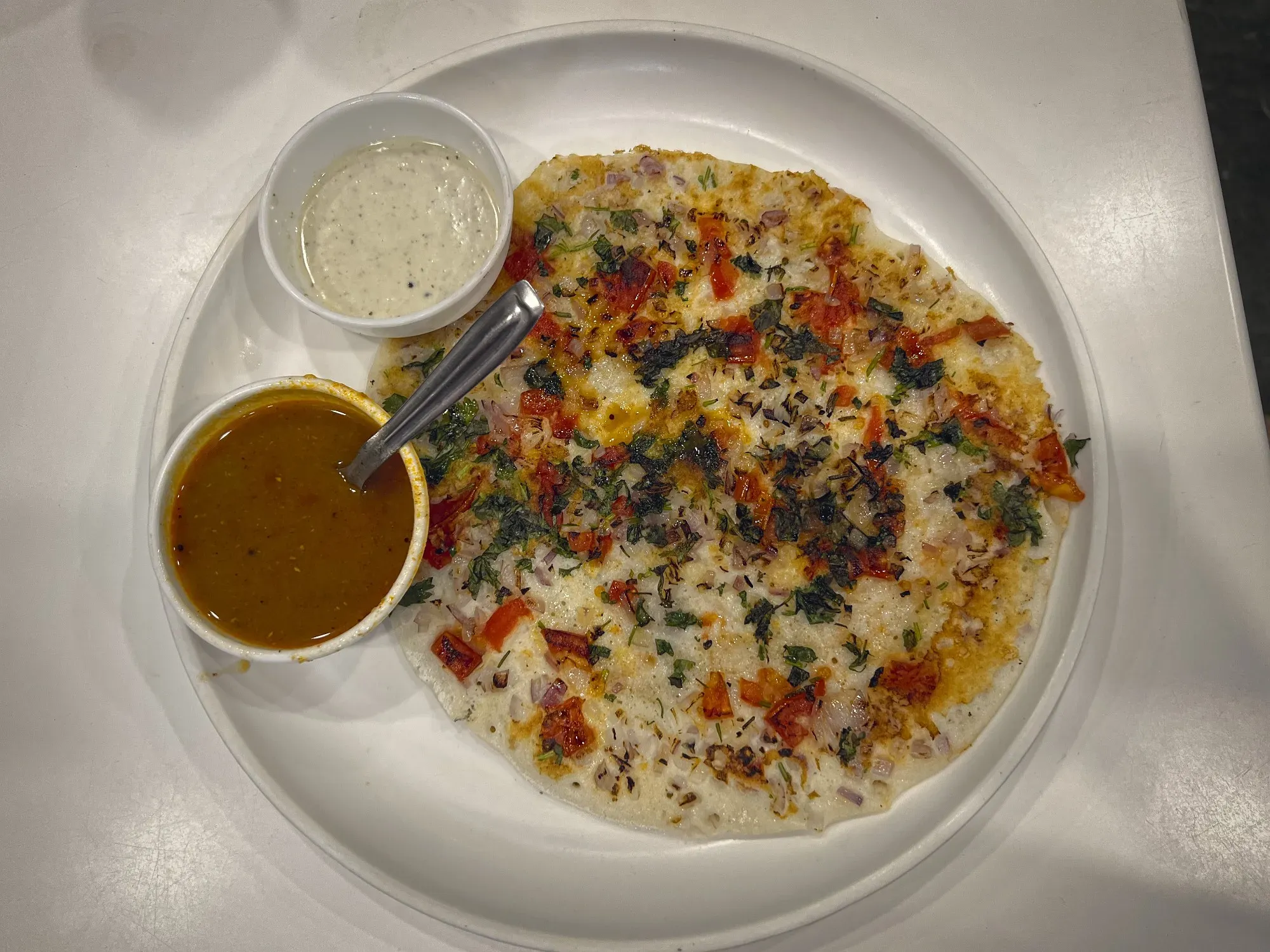 Overhead shot of Uttapam on a plate with two dipping sauces.