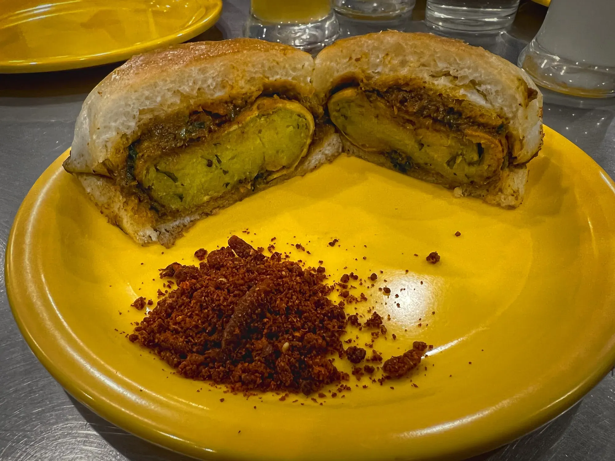 A Vada Pav cut down the middle, opened to show the inside of the sandwich, low shot.