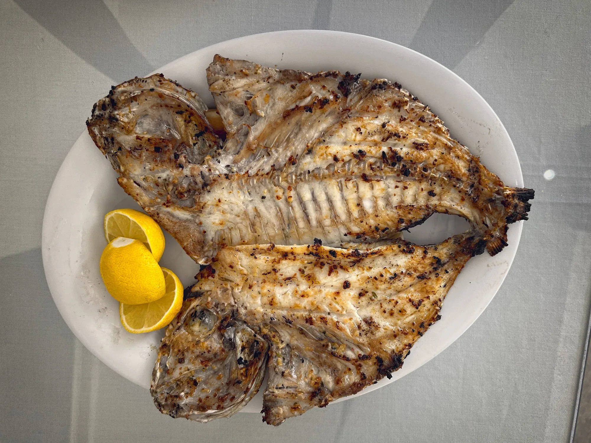 A whole fish split in half and opened up on the plate, overhead shot.