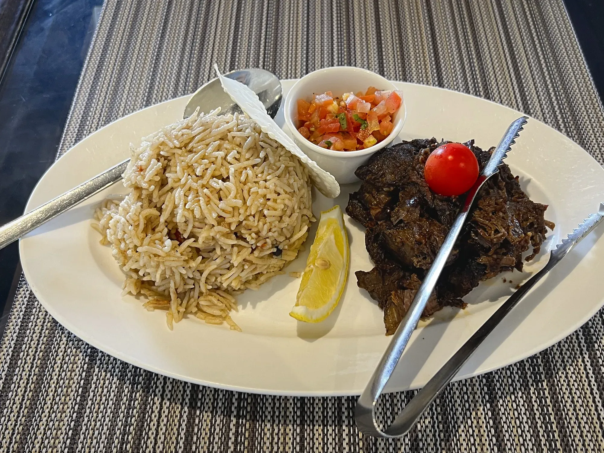 Plate of shuwa with side of rice, angled shot.