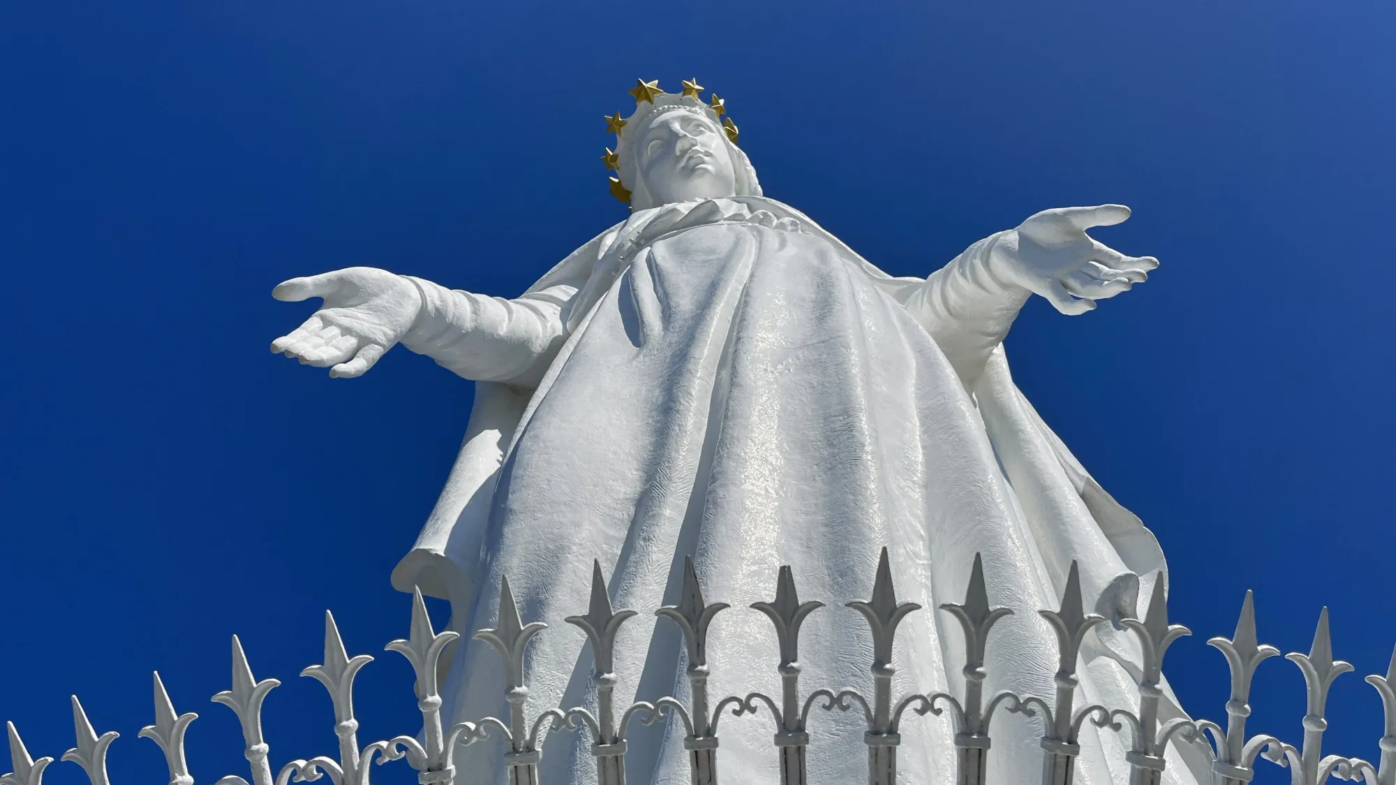 Looking up at the outstretched hands of the white statue of Our Lady of Lebanon