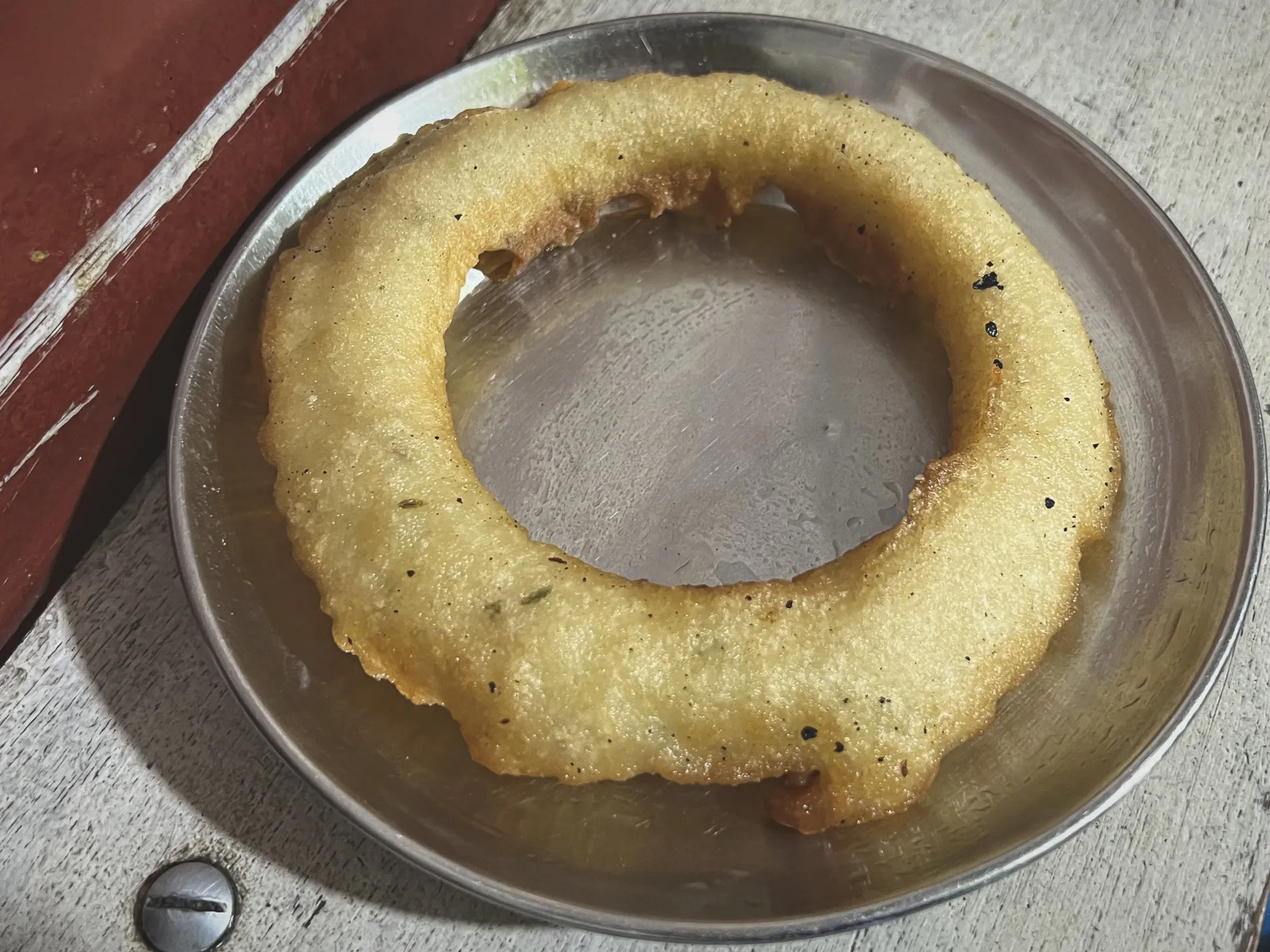 Close-up, angled shot of Sel Roti on a small silver plate.