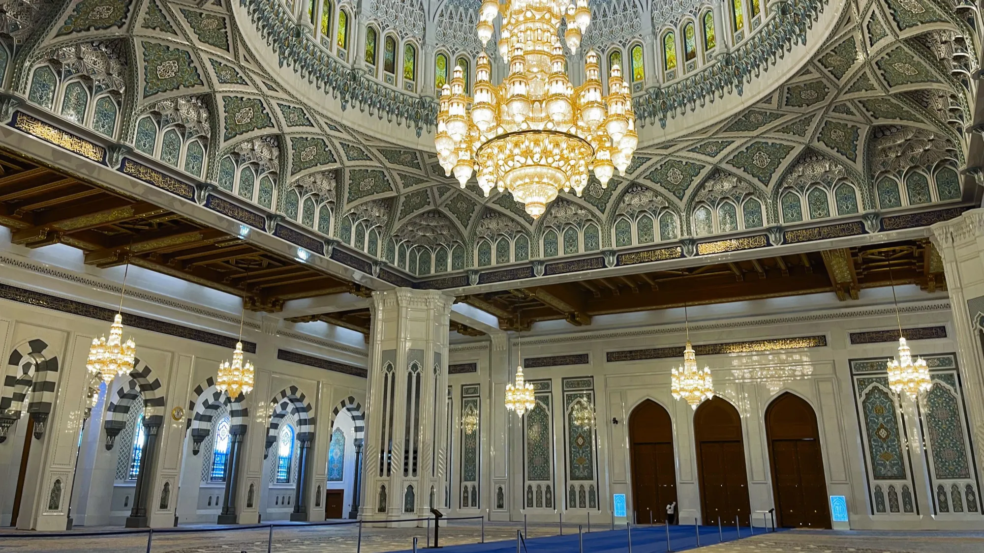 Blue, white, and green tiled interior of the Sultan Qaboos Grand Mosque