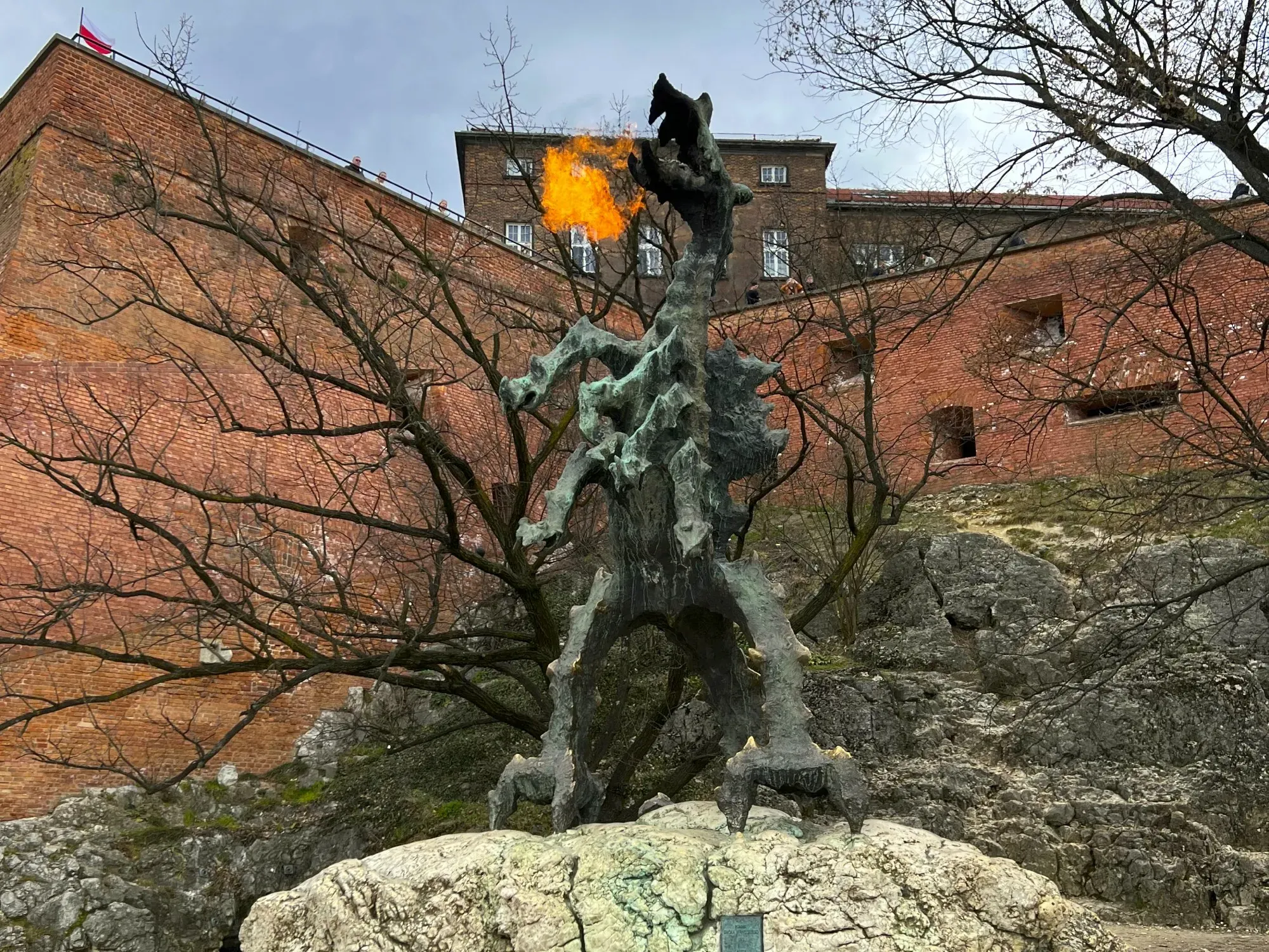 Large fire breathing dragon statue in front of a brick wall