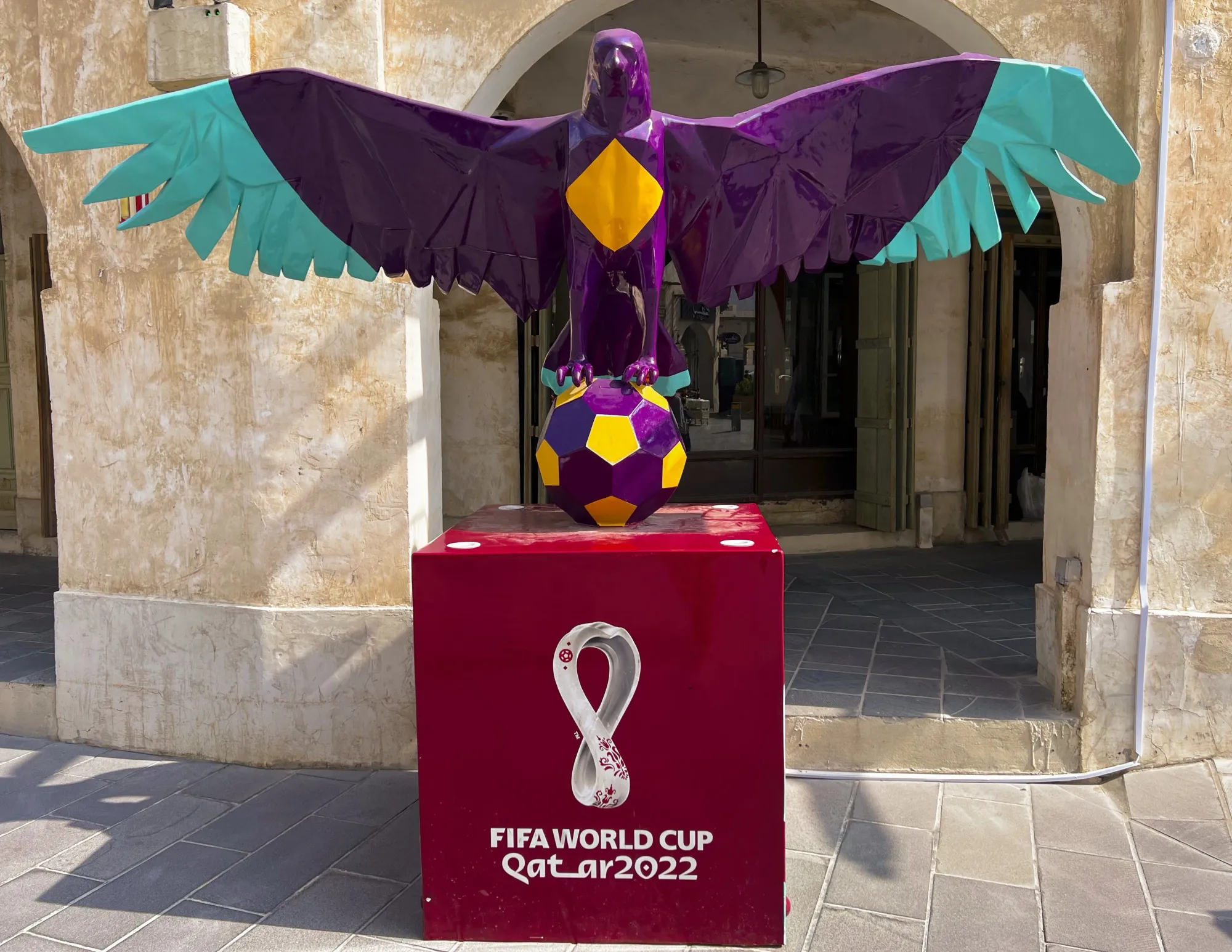 A purple statue of a falcon perched on a soccer ball above a box for the 2022 FIFA World Cup