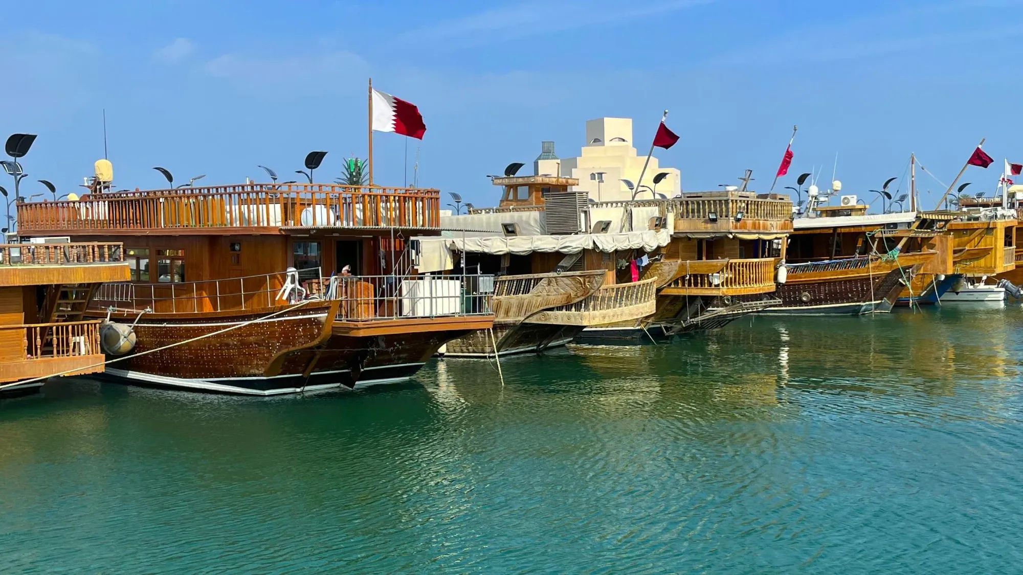 A lineup of Qatari dhows flying national flags