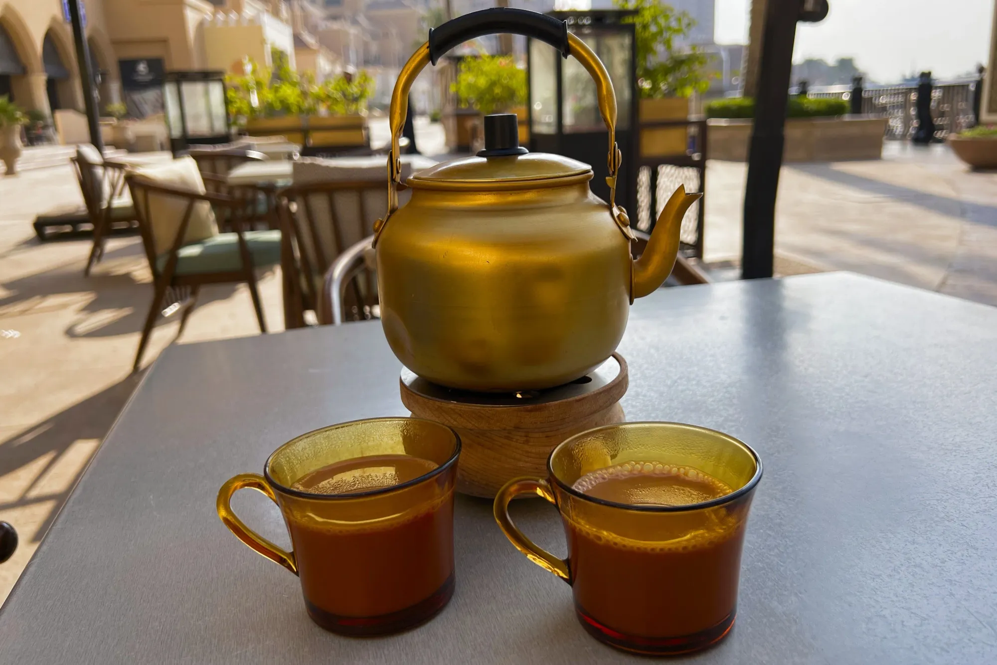 Gold teapot with two cups filled with karak tea