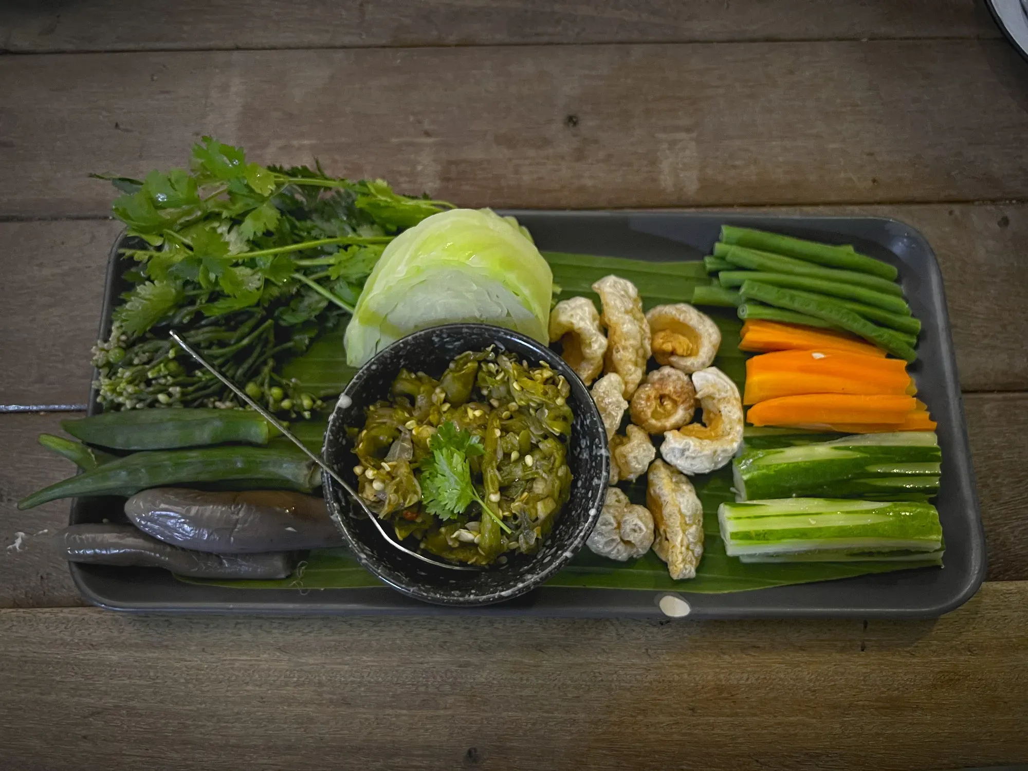 Overhead shot of a platter of vegetables with a dipping bowl of Nam Prik Noom Kab Moo.