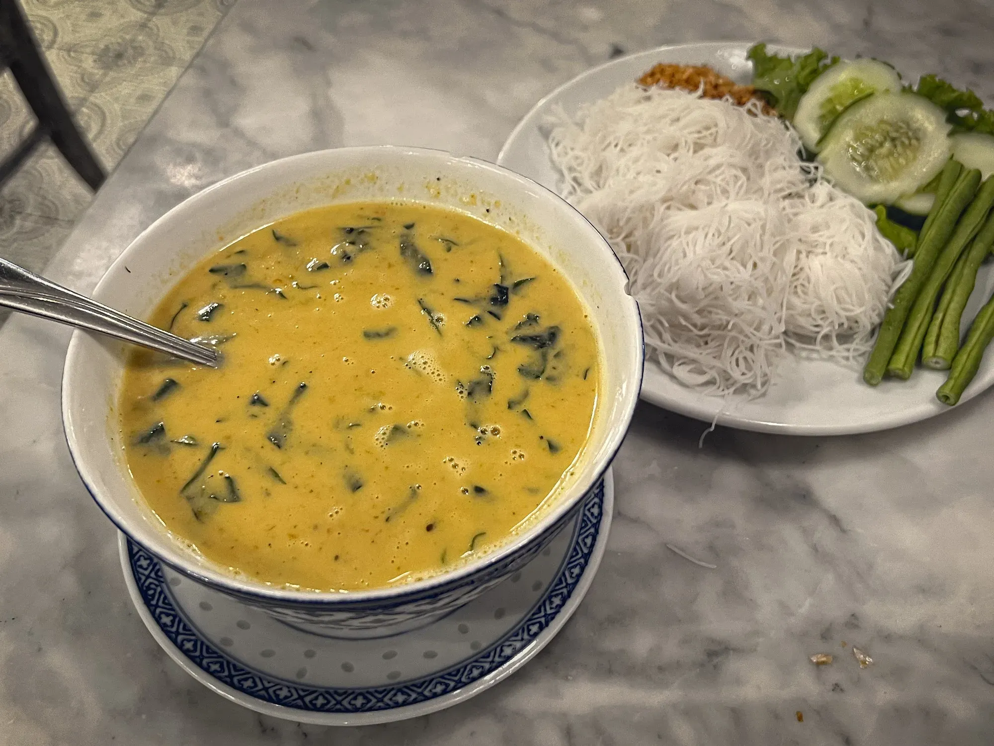 Sen Mee Gaeng Poo in a bowl with rice noodles and sides on a plate.