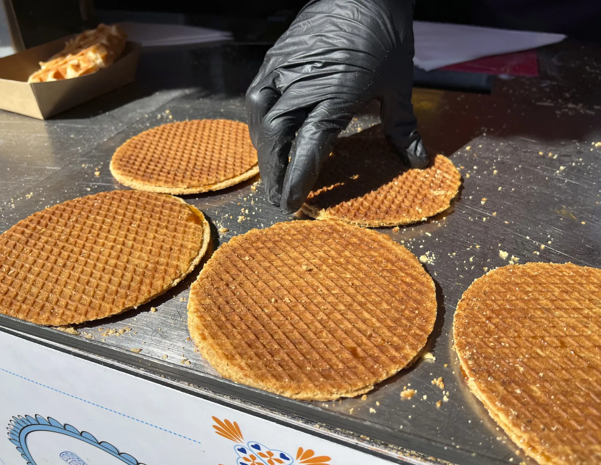 Flat Dutch waffles being served by a gloved hand