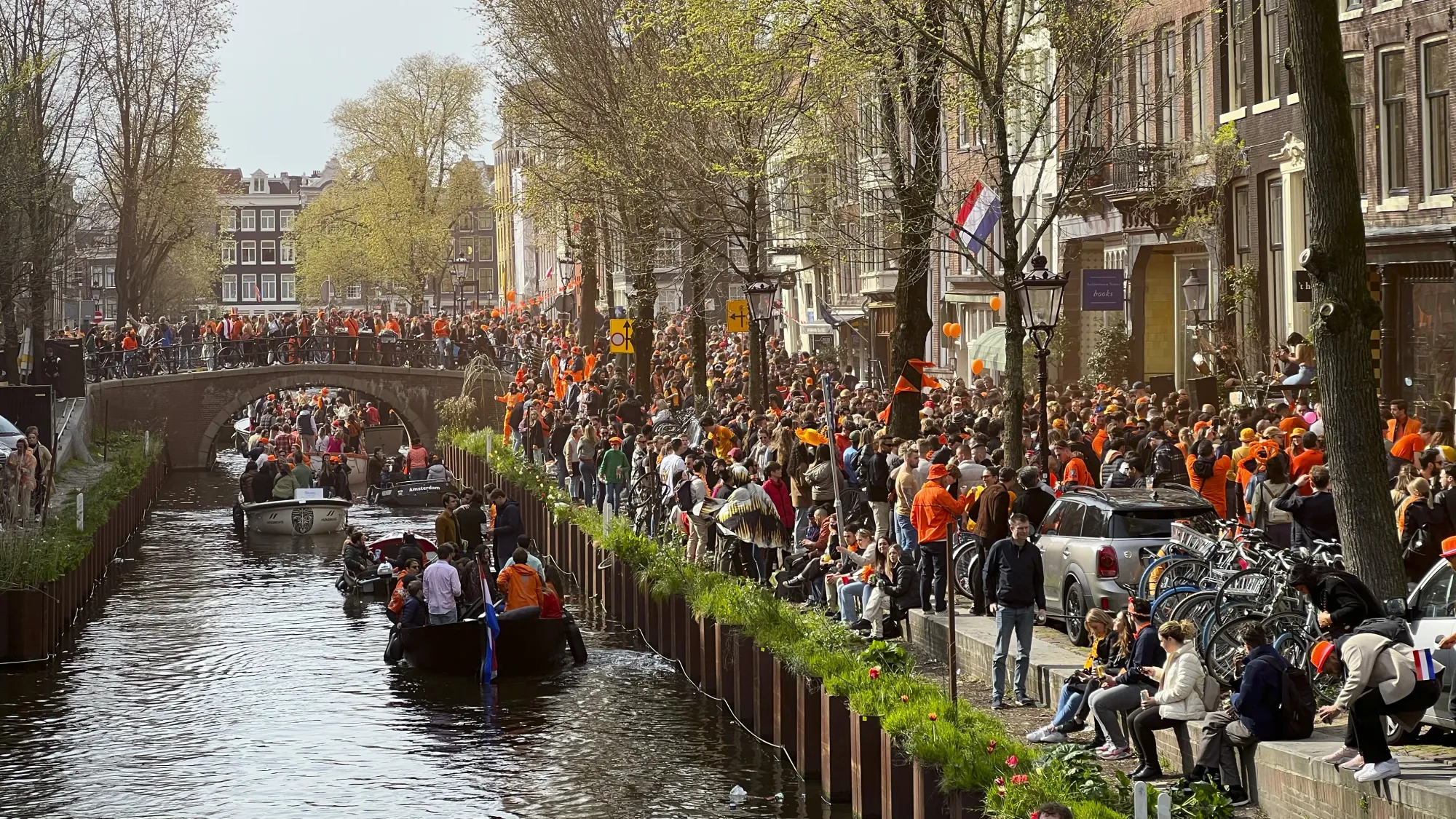 Masses of people dressed in orange celebrating King's Day along the canal