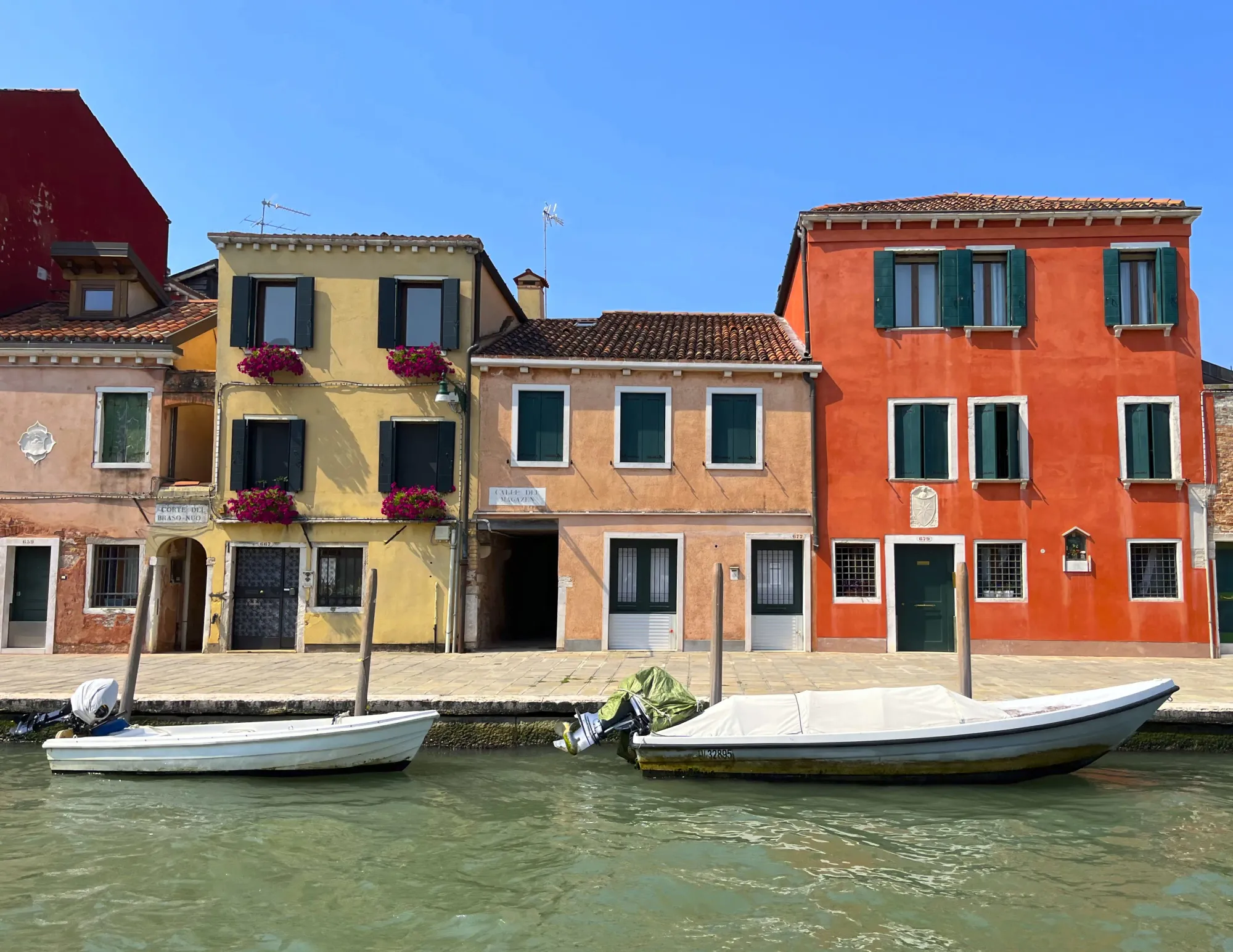 Pastel home fronts with two white boats moored in the water