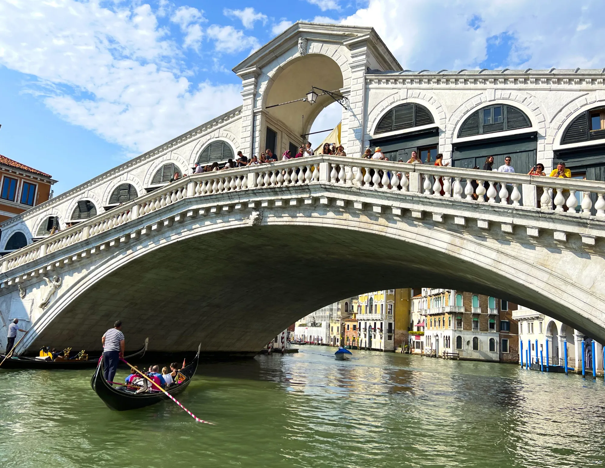 White arched bridge with a gondola passing under it