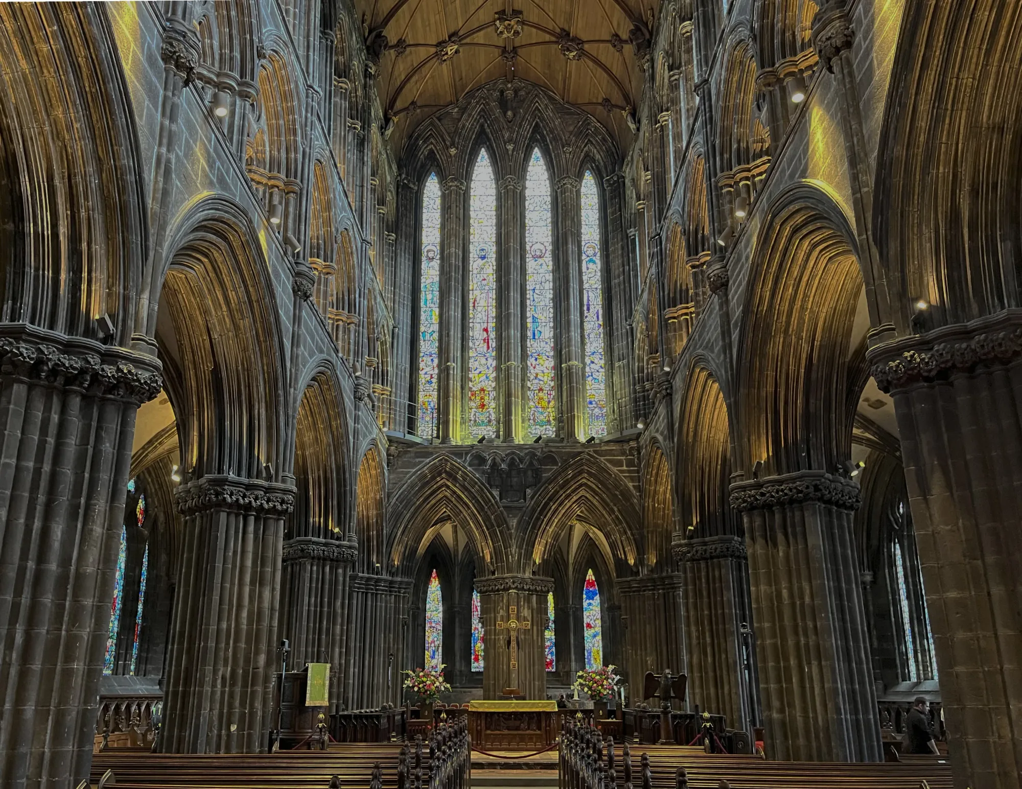 Dark church shot from the center aisle looking at the altar backed with stained glass