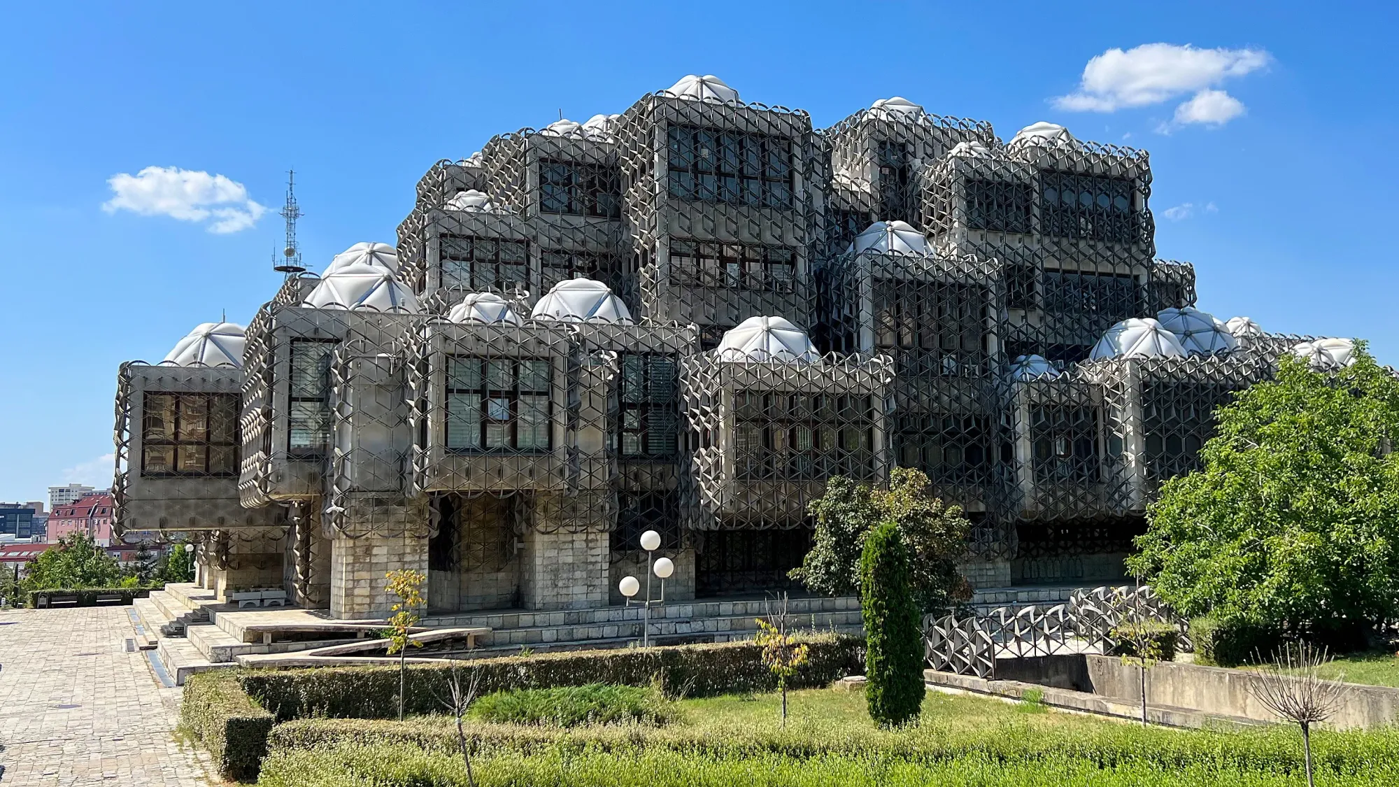 Grey concrete building covered in black mesh cages with white angular domes on top