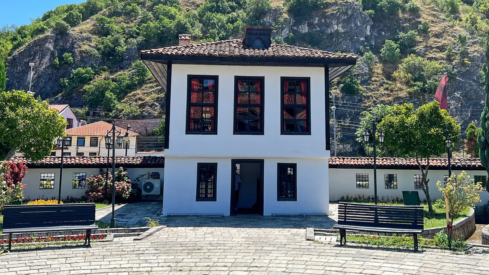 White building with black windows set at the foot of a tree covered hill