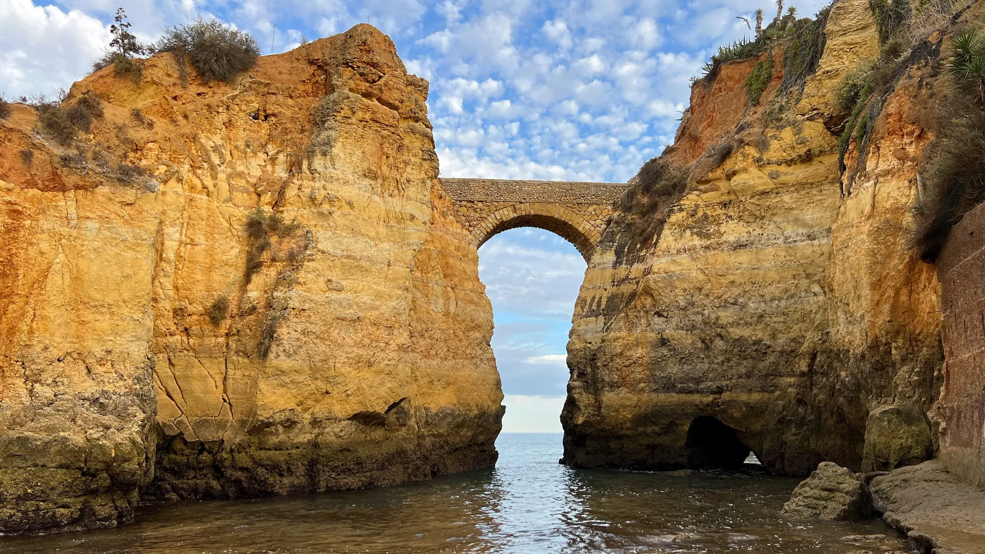 Rocks coming out of the water with a stone bridge between them