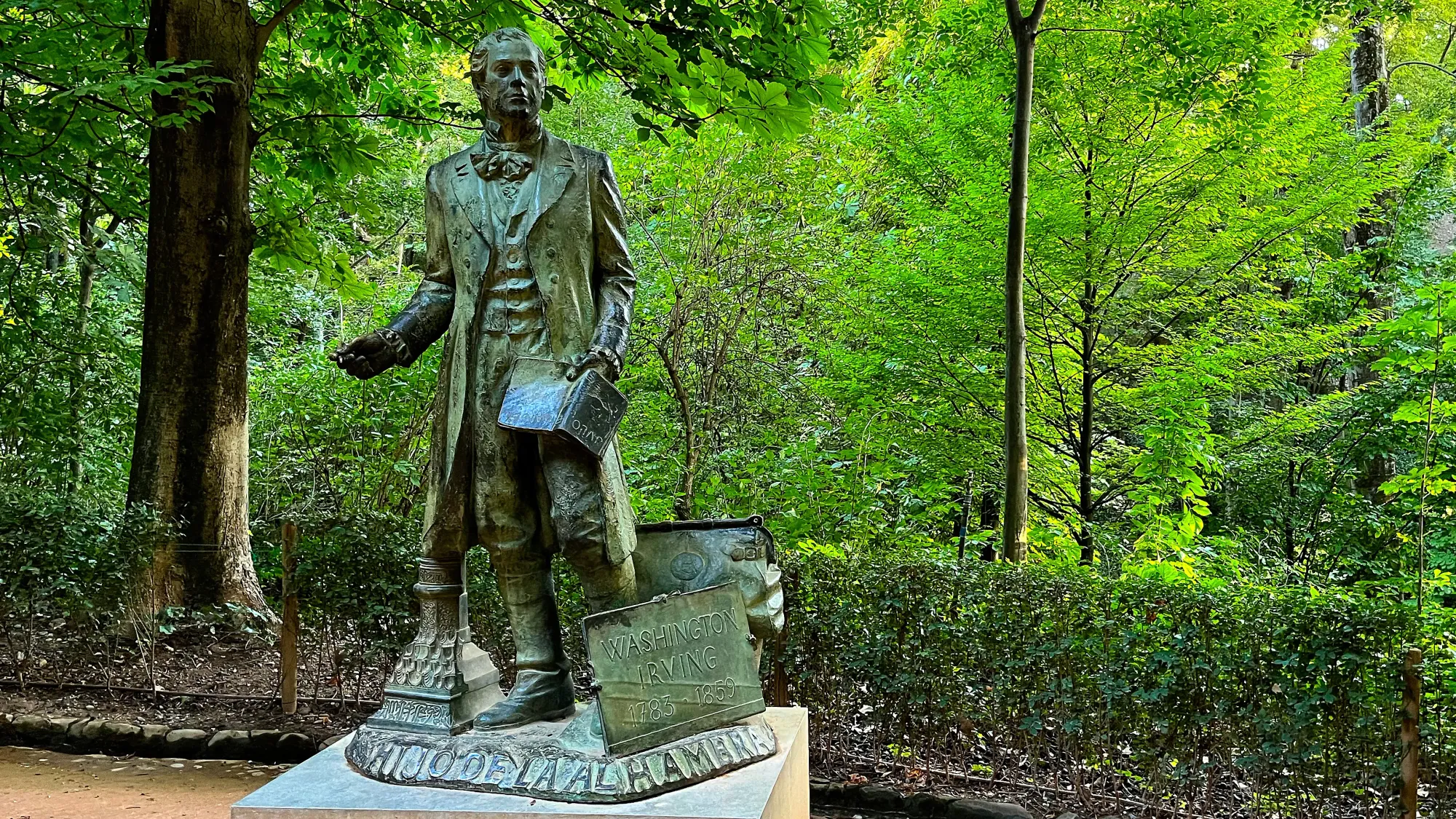 Green statue of Washinton Irving in front of trees