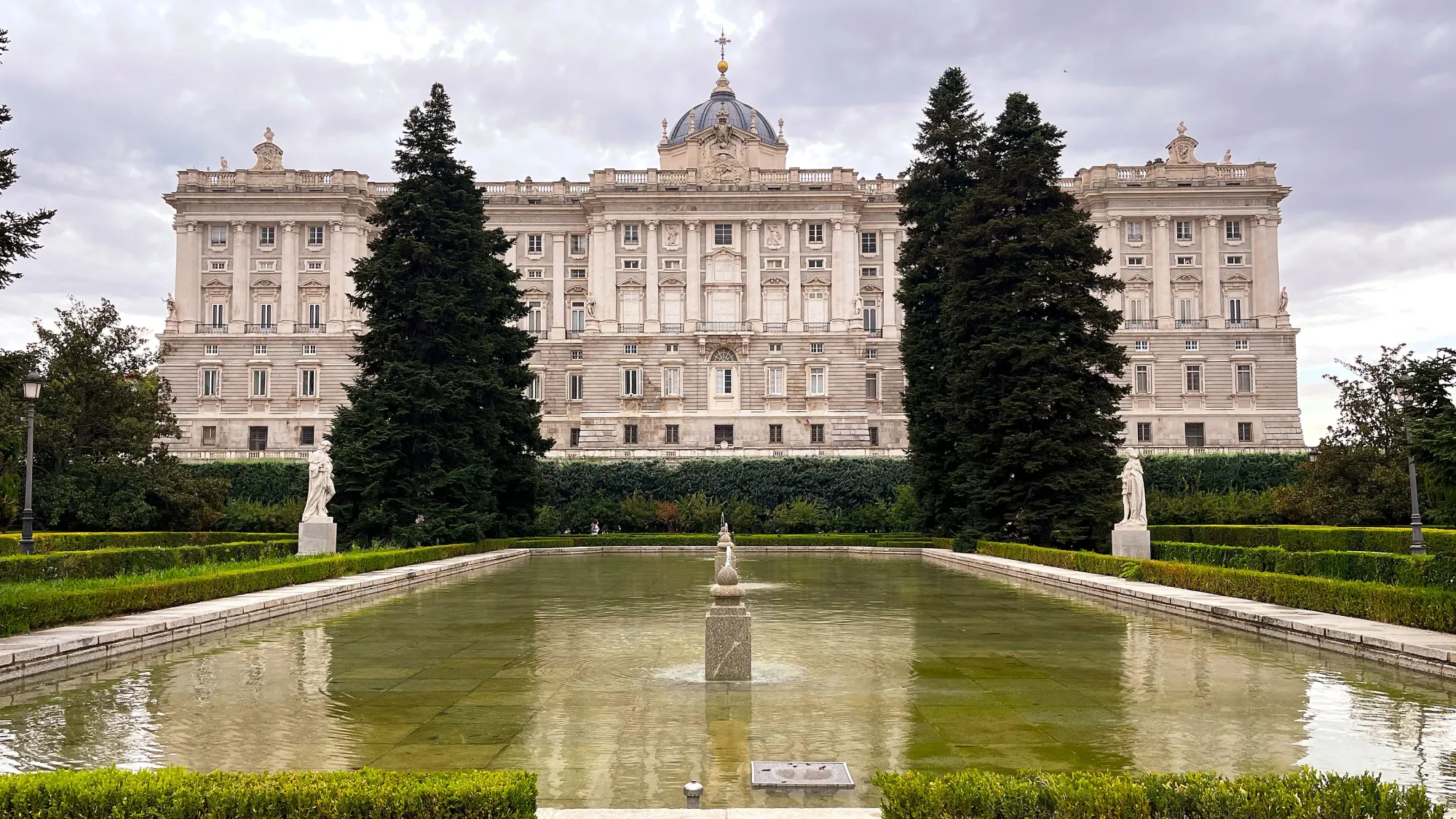 White palace overlooking a reflecting pool with tall trees on either side