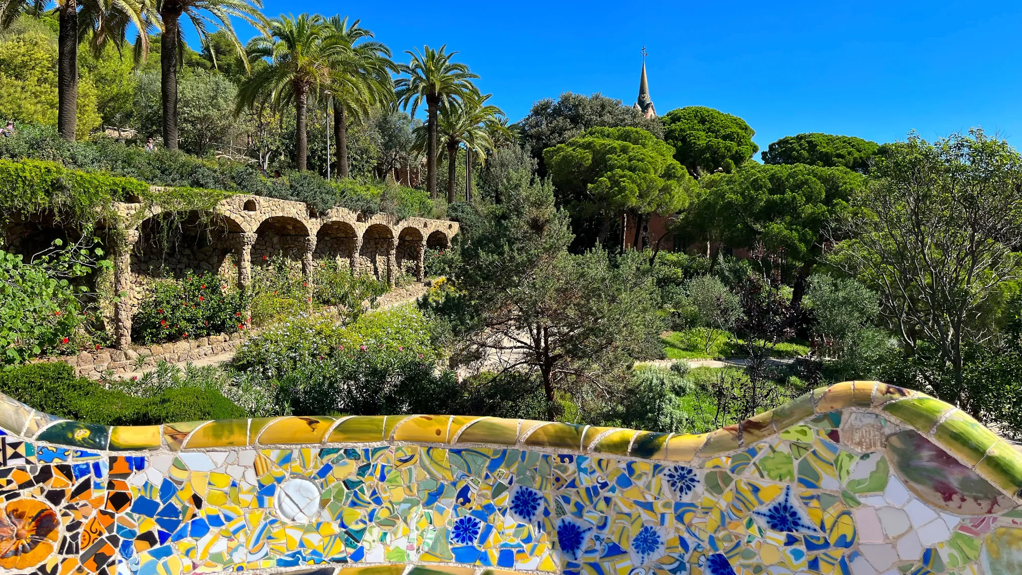 Tiled balcony overlooking a park with arches and palm trees