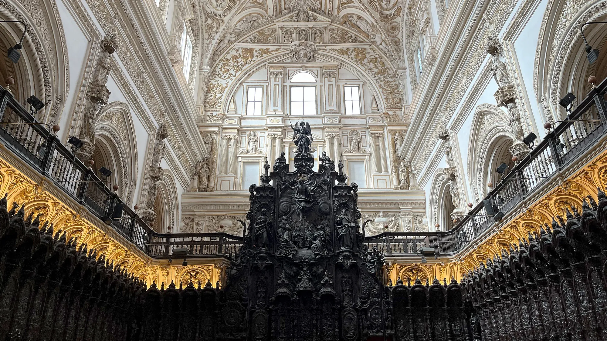 Black wooded seating with ornate white ceiling